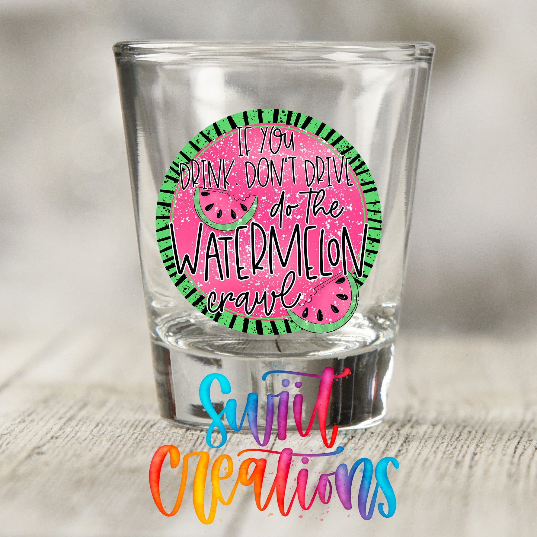 A shot glass with a colorful design featuring a watermelon slice and the text "If you drink don't drive, don't do the watermelon crawl" printed on it.
