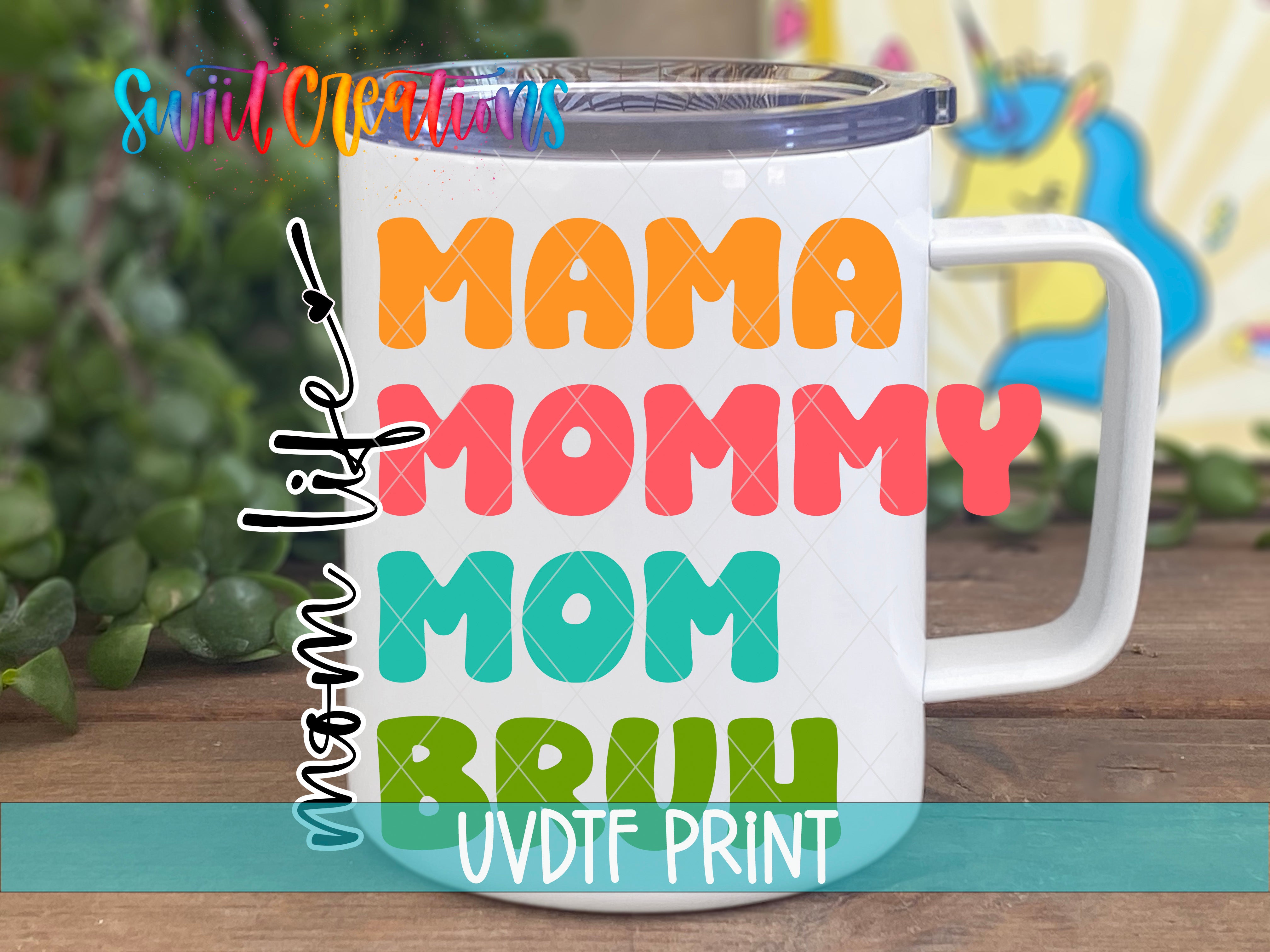 A white mug with colorful text that says "Mama Mommy Mommy" printed on it, placed on a wooden surface with a blurred background.