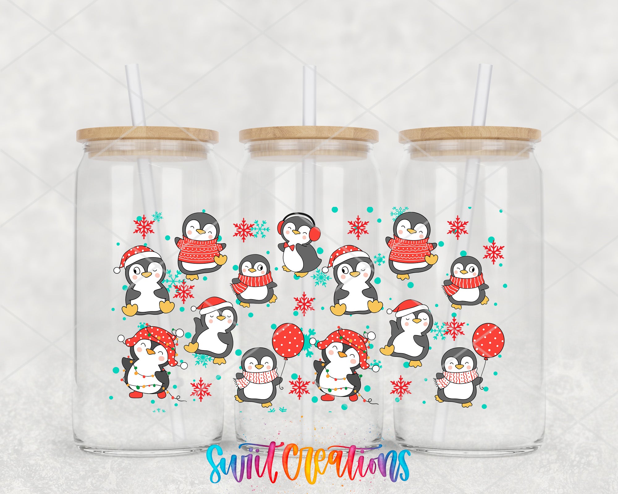 A collection of three glass tumblers with a festive design featuring cartoon penguins and snowflakes.