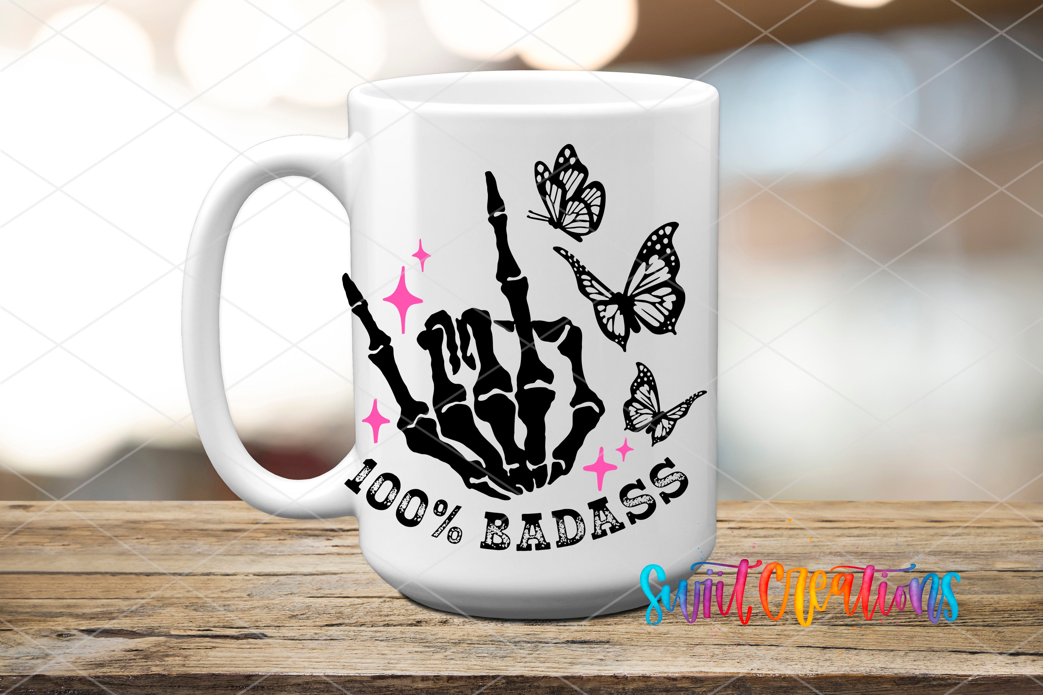 A white mug with a graphic design featuring a skeleton hand making a rock and roll sign, surrounded by butterflies and the text "100% BADASS".