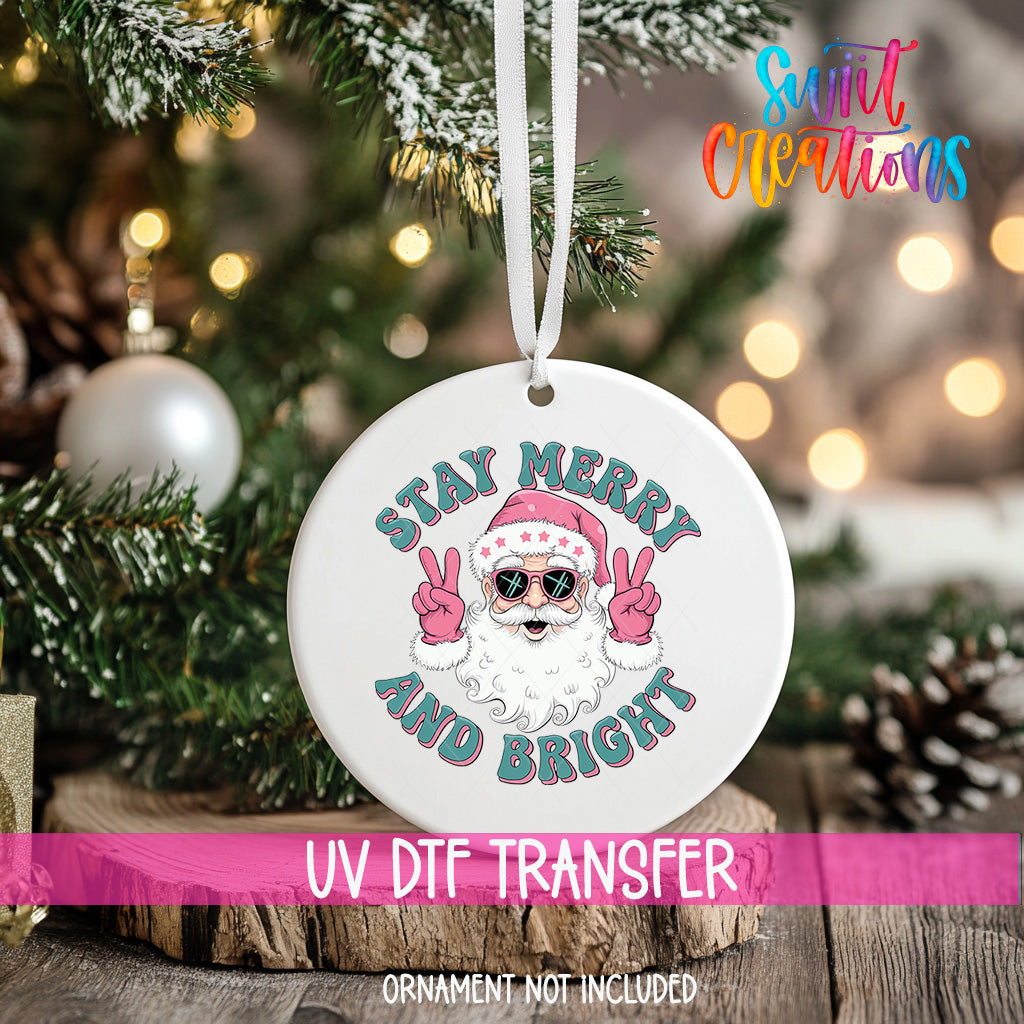 A white ornament with a Santa Claus design and the text "STAY MERRY AND BRIGHT" hanging on a Christmas tree.