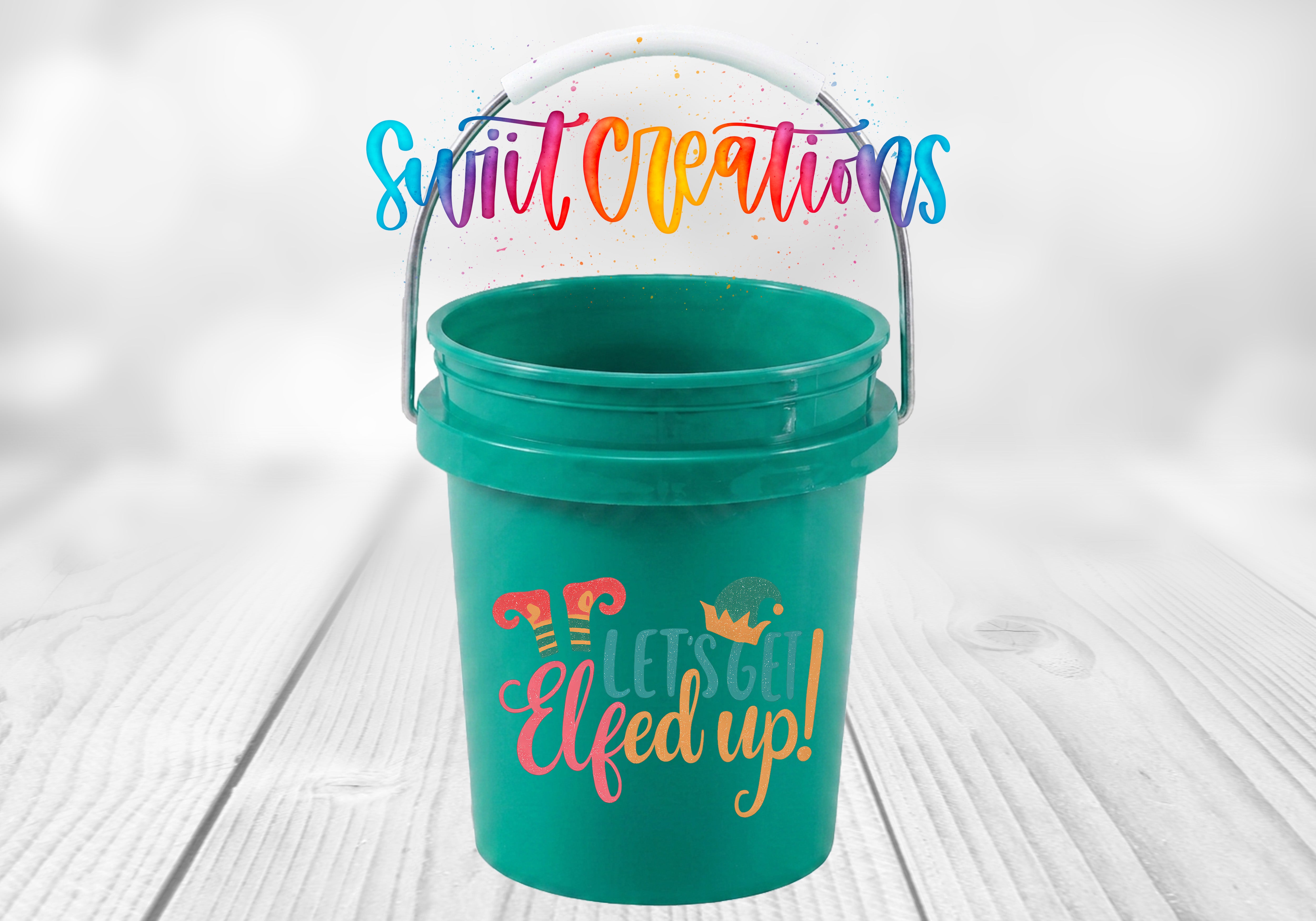A green bucket with a handle and a colorful, whimsical text design on it, placed on a wooden surface.