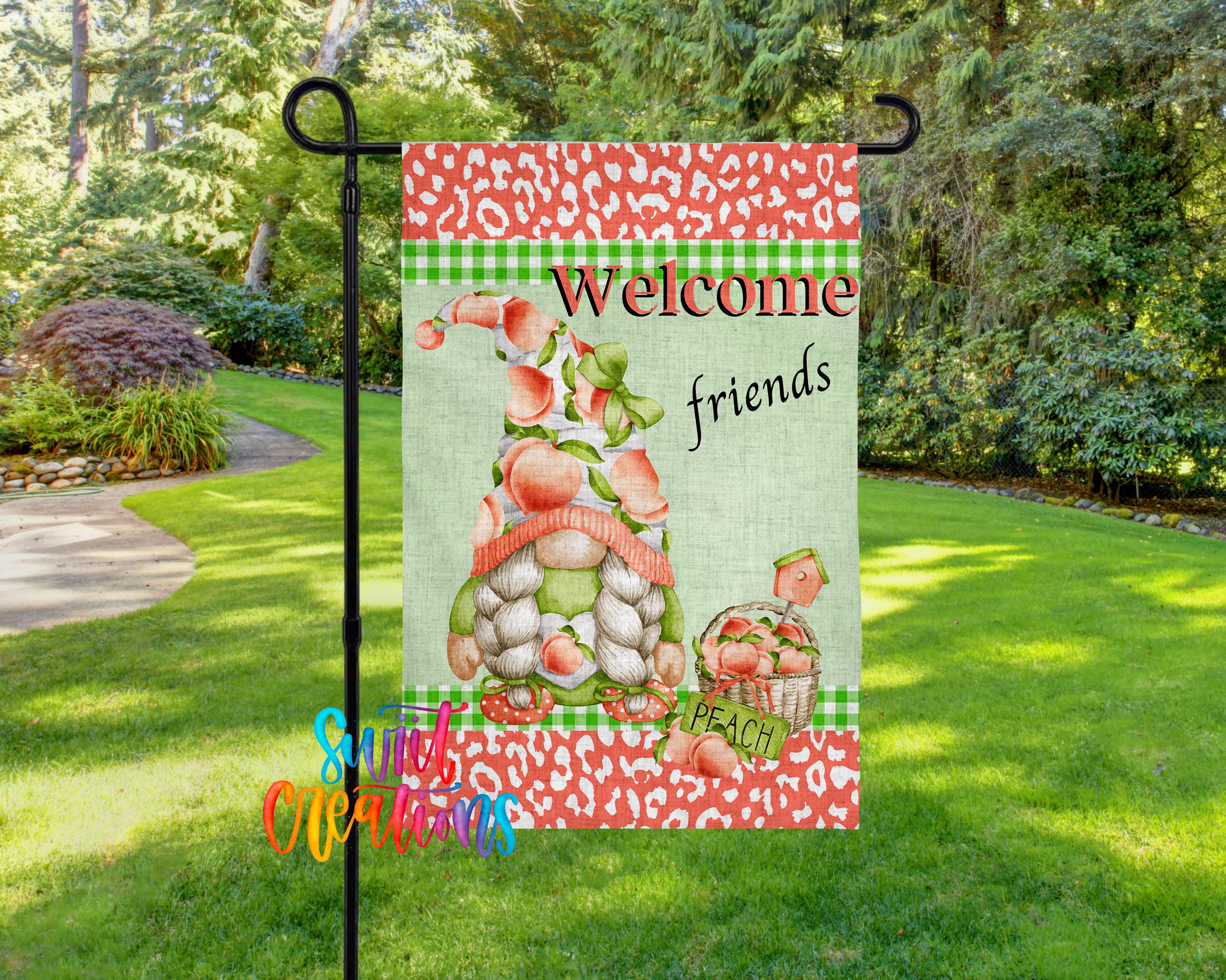 A colorful garden gnome sign with the text "Welcome friends peach" displayed on it, set against a backdrop of lush greenery and a path in a park-like setting.