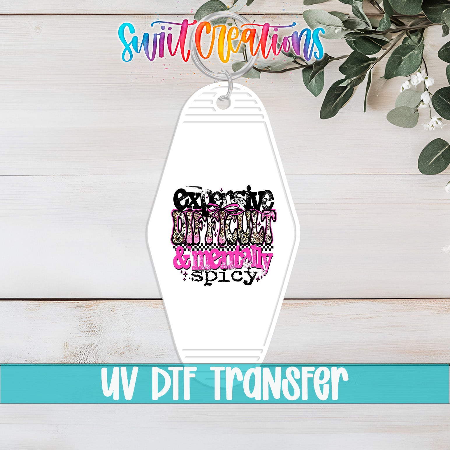A white keychain with a colorful graphic design featuring the text "Exclusive Difficulty & Meats spicy" printed on it, placed on a wooden surface with greenery in the background.