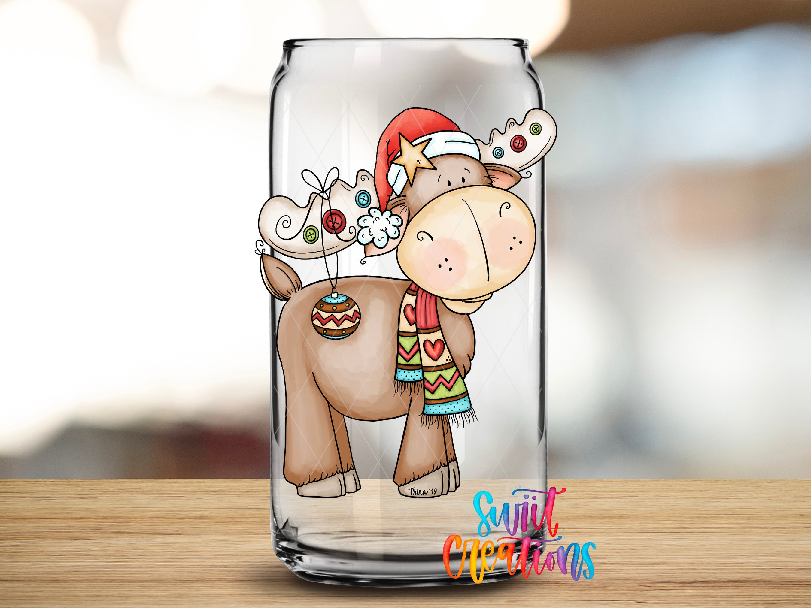 A glass can with a cartoon illustration of a moose wearing a Santa hat and scarf, along with other Christmas-themed decorations.