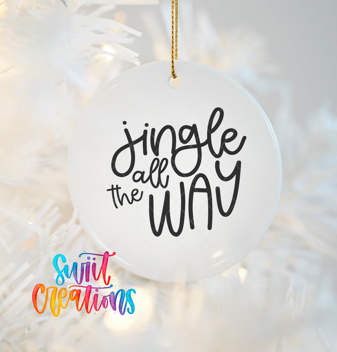 A white ornament with the text "Jingle all the way" written on it, hanging on a Christmas tree.