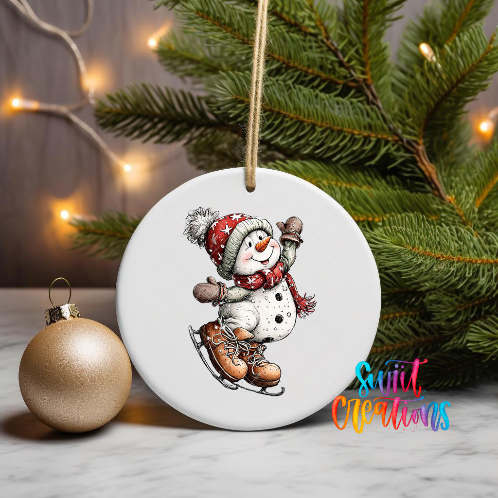 A white ornament featuring a snowman is displayed on a white surface, with a Christmas tree and a gold ornament visible in the background.