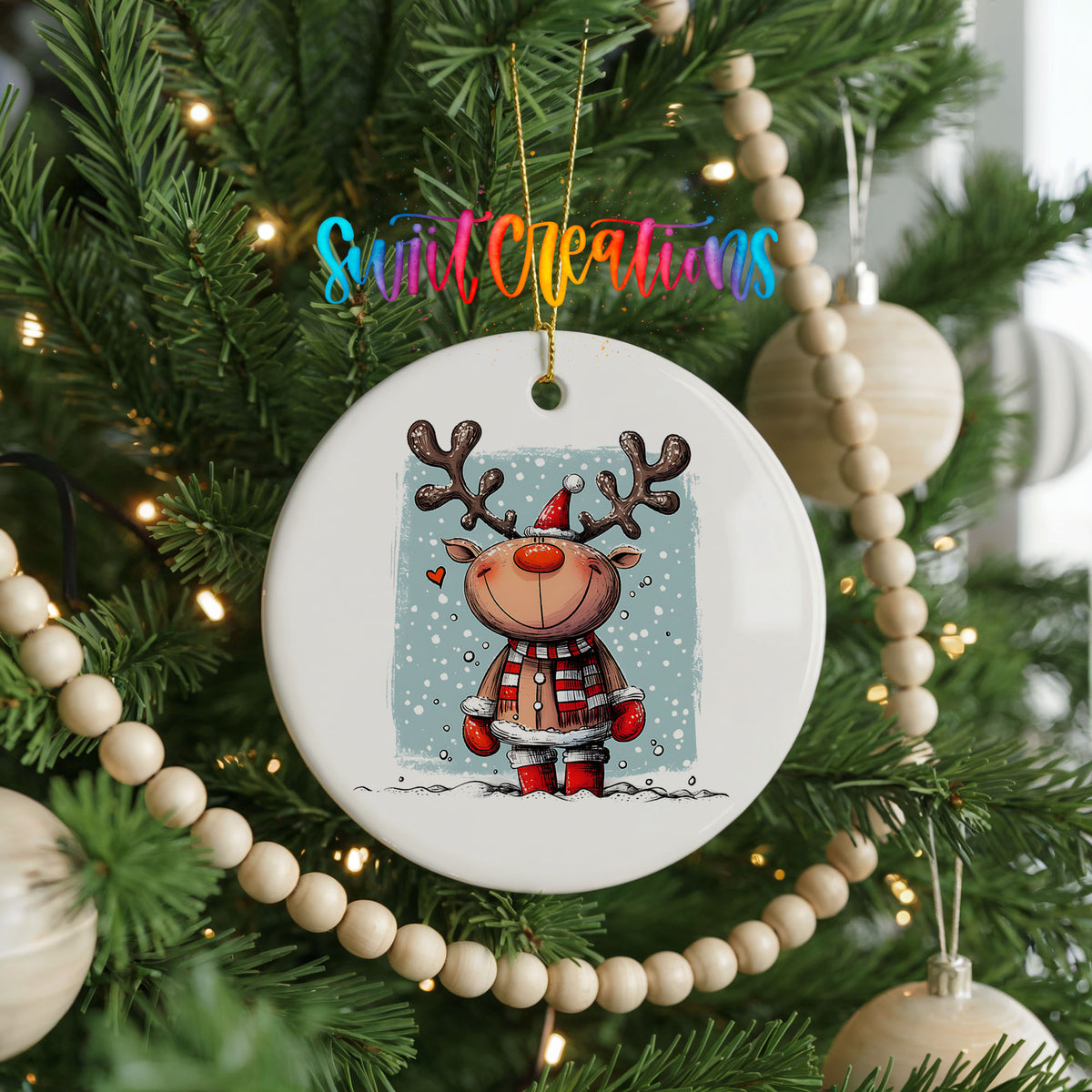 A white ceramic ornament featuring a cartoon reindeer is hanging on a Christmas tree, surrounded by ornaments and lights.