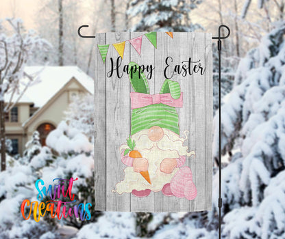 A wooden Easter banner with a gnome holding a carrot and a banner with the text "Happy Easter" is displayed in front of a snowy house.