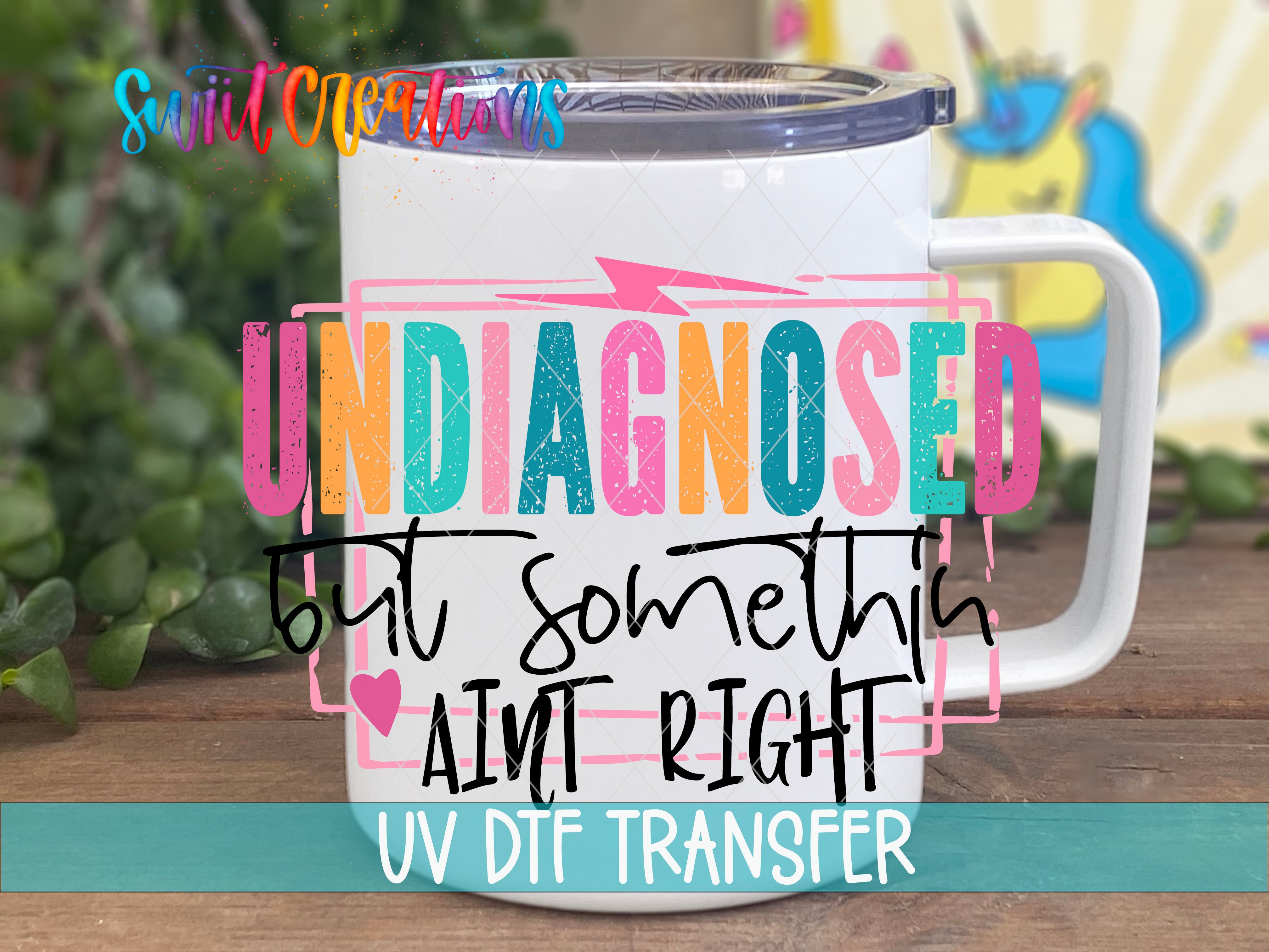 A white mug with colorful text and graphics on it, placed on a wooden surface.