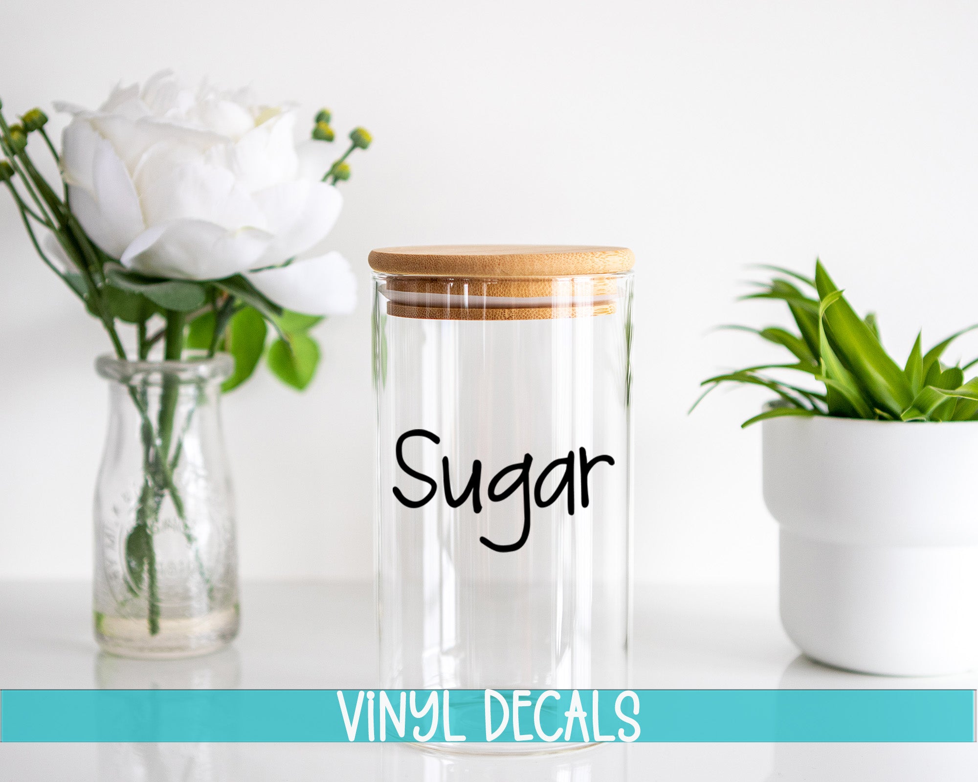 a glass jar with a wooden lid sitting next to a vase with a white flower