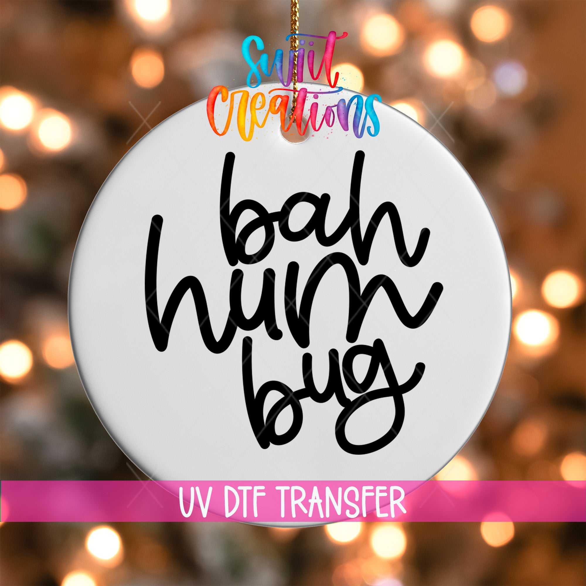 A white ornament with the text "bah hum bug" written on it, hanging against a background of colorful lights.