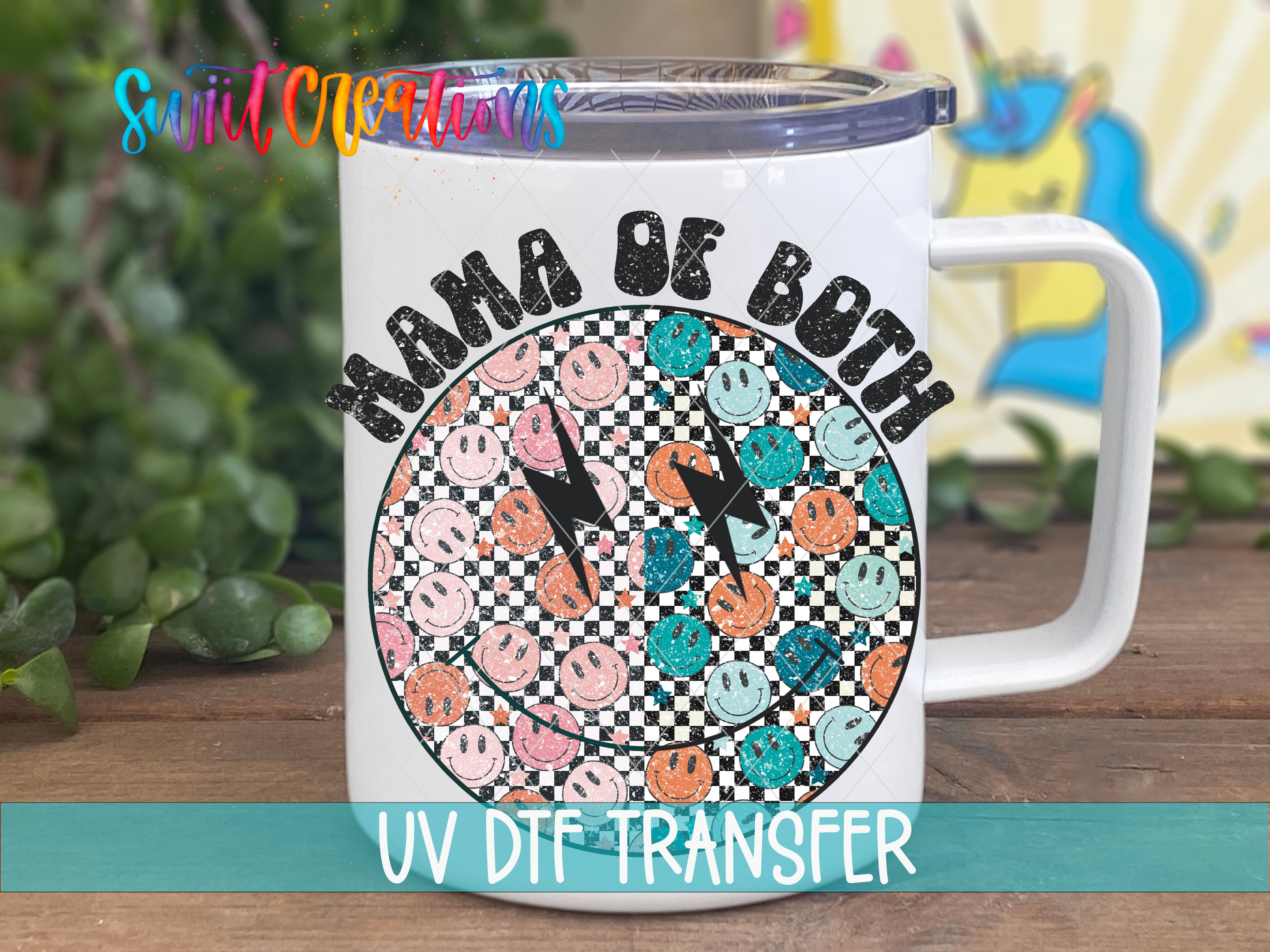 A white mug with a colorful graphic design featuring a checkerboard pattern of smiley faces and the text "Mama of both" printed on it.