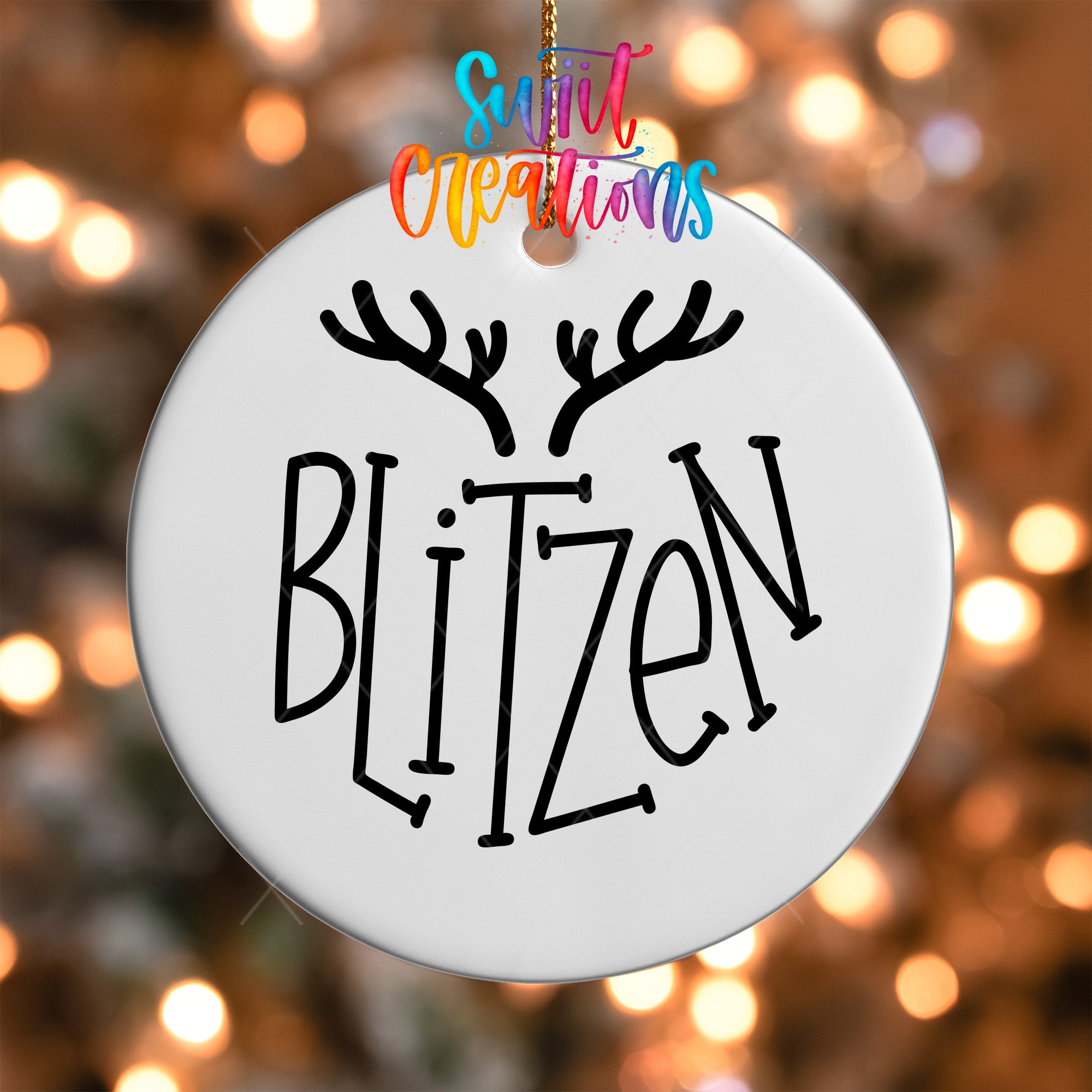 A white ornament with the word "BLITZEN" written on it, hanging against a background of colorful lights.