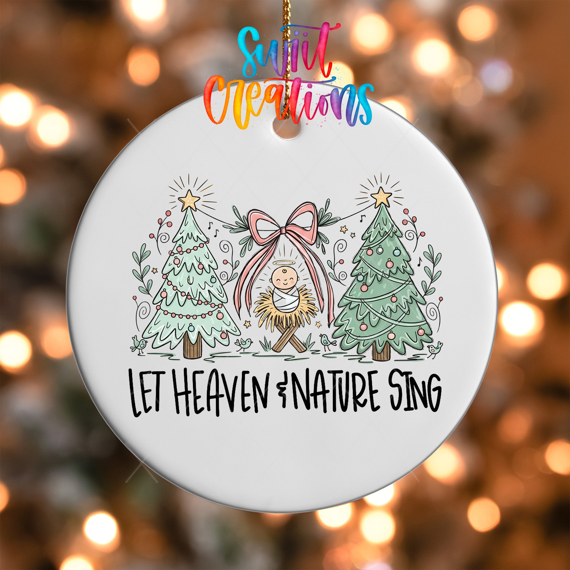 A white ornament with a Christmas tree design and a baby Jesus, along with the text "Let Heaven & Nature Sing" written on it.