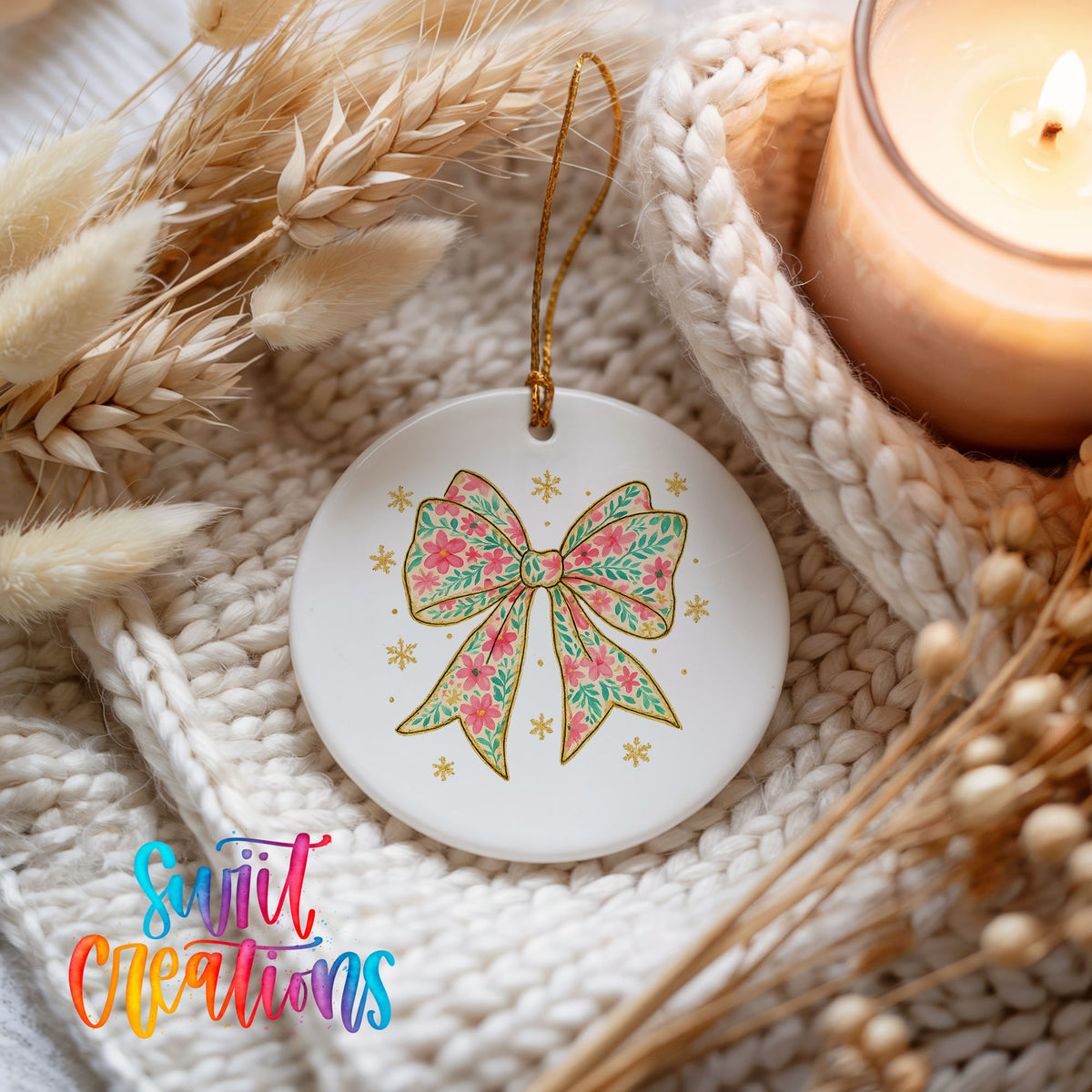 A white ceramic ornament with a floral bow design and gold accents, placed on a white knitted blanket with dried flowers and a lit candle.