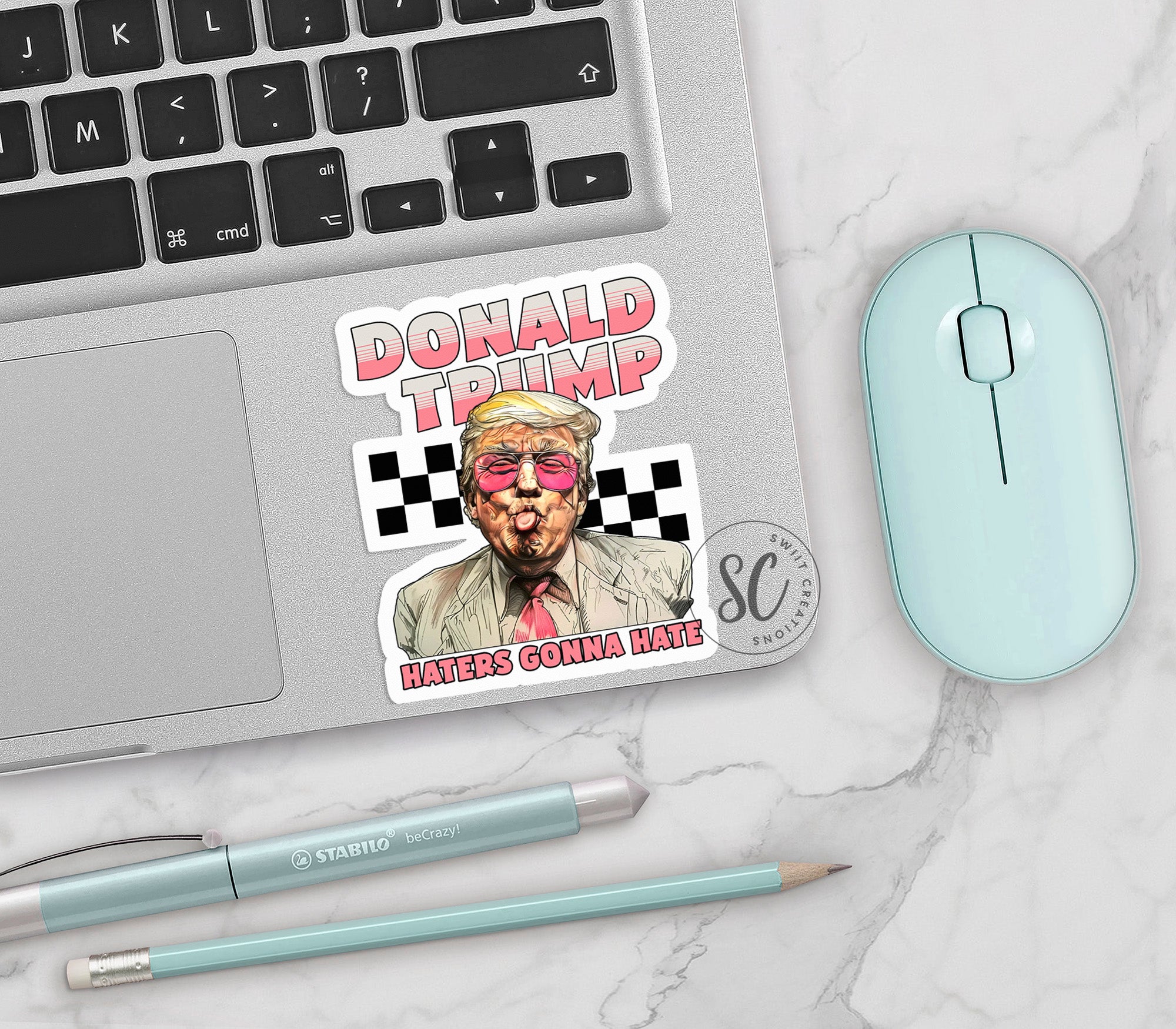 a sticker of donald trump on a laptop next to a mouse