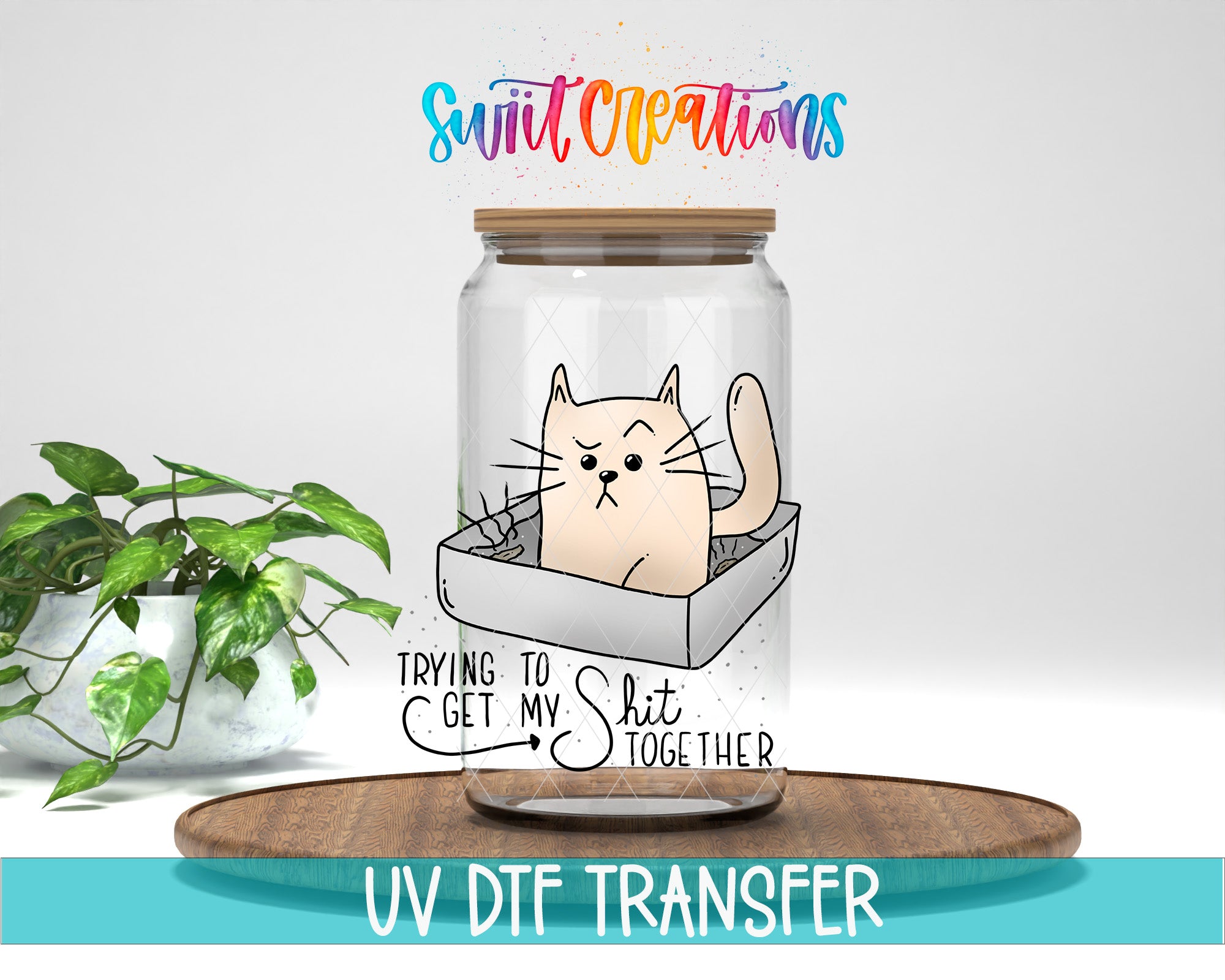 A glass jar containing a cartoon cat, with the text "Trying to get my shit together" written on it. The jar is placed on a wooden surface, and there is a potted plant in the background.