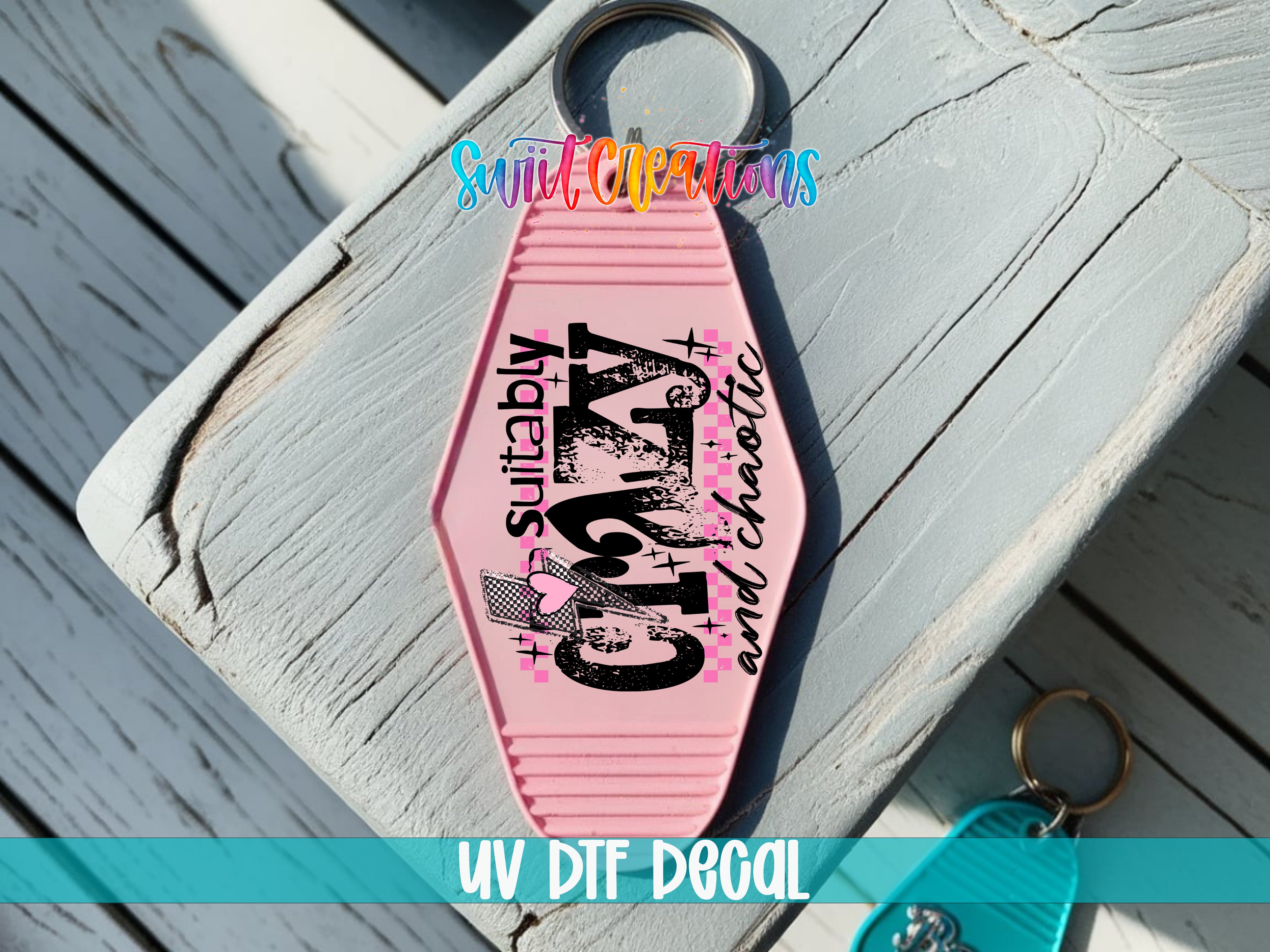 A pink keychain with the text "Suitablely" and "Chocolate" printed on it, placed on a wooden surface.