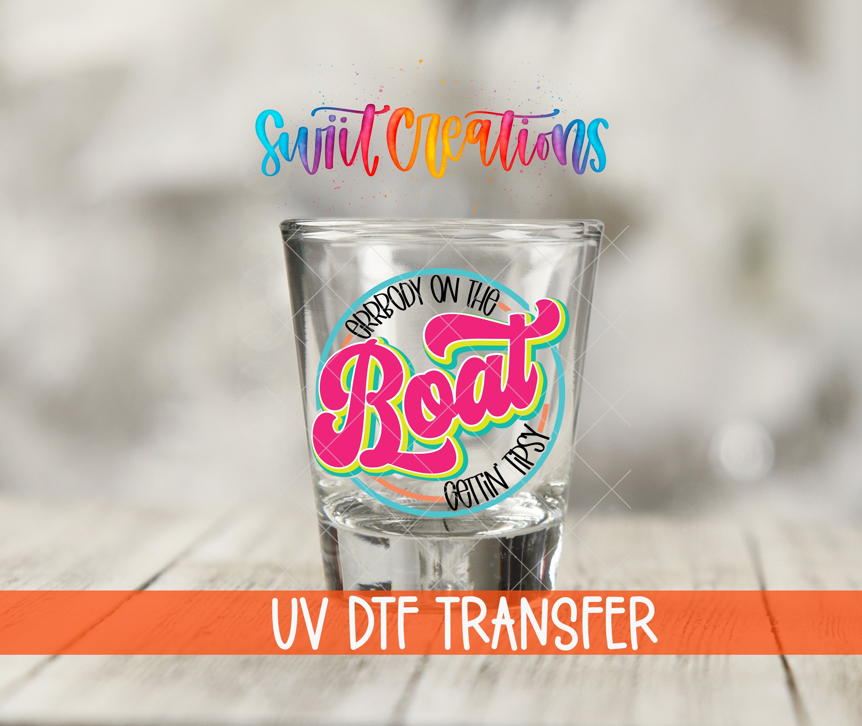 A shot glass with a colorful design and text on it, placed on a wooden surface.