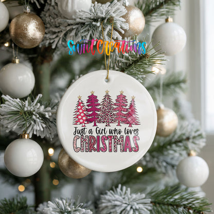 A Christmas tree decorated with white ornaments and a ceramic ornament with a pink and white design hanging from the tree.