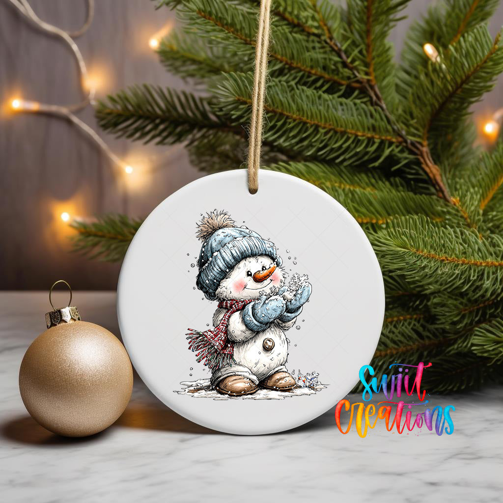 A white ceramic ornament featuring a snowman is displayed on a table, with a Christmas tree and twinkling lights in the background.