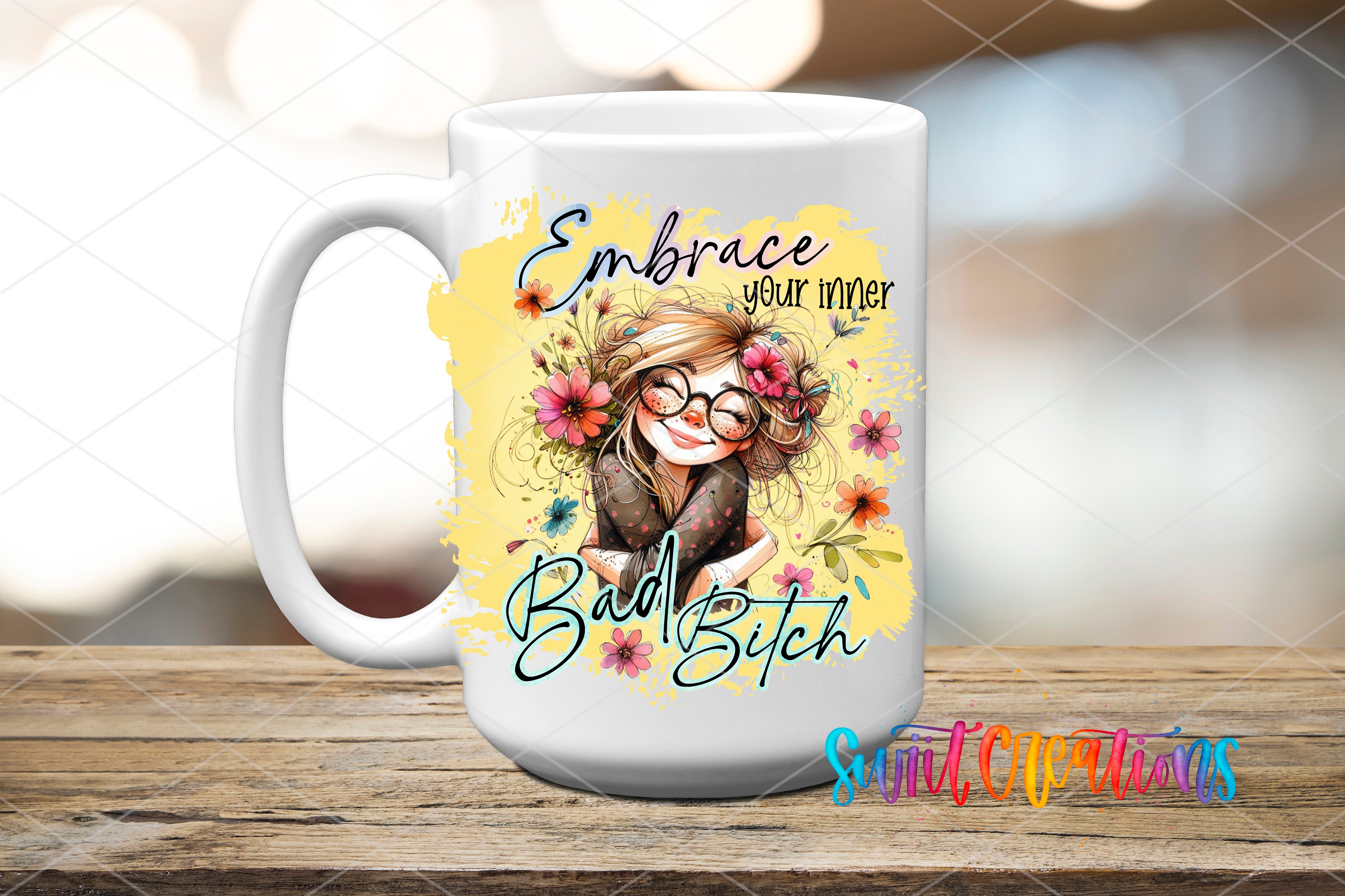 A white ceramic mug with a colorful illustration of a smiling woman with flowers in her hair, along with the text "Embrace your inner Bitch" and "Bad Bitch" printed on it.