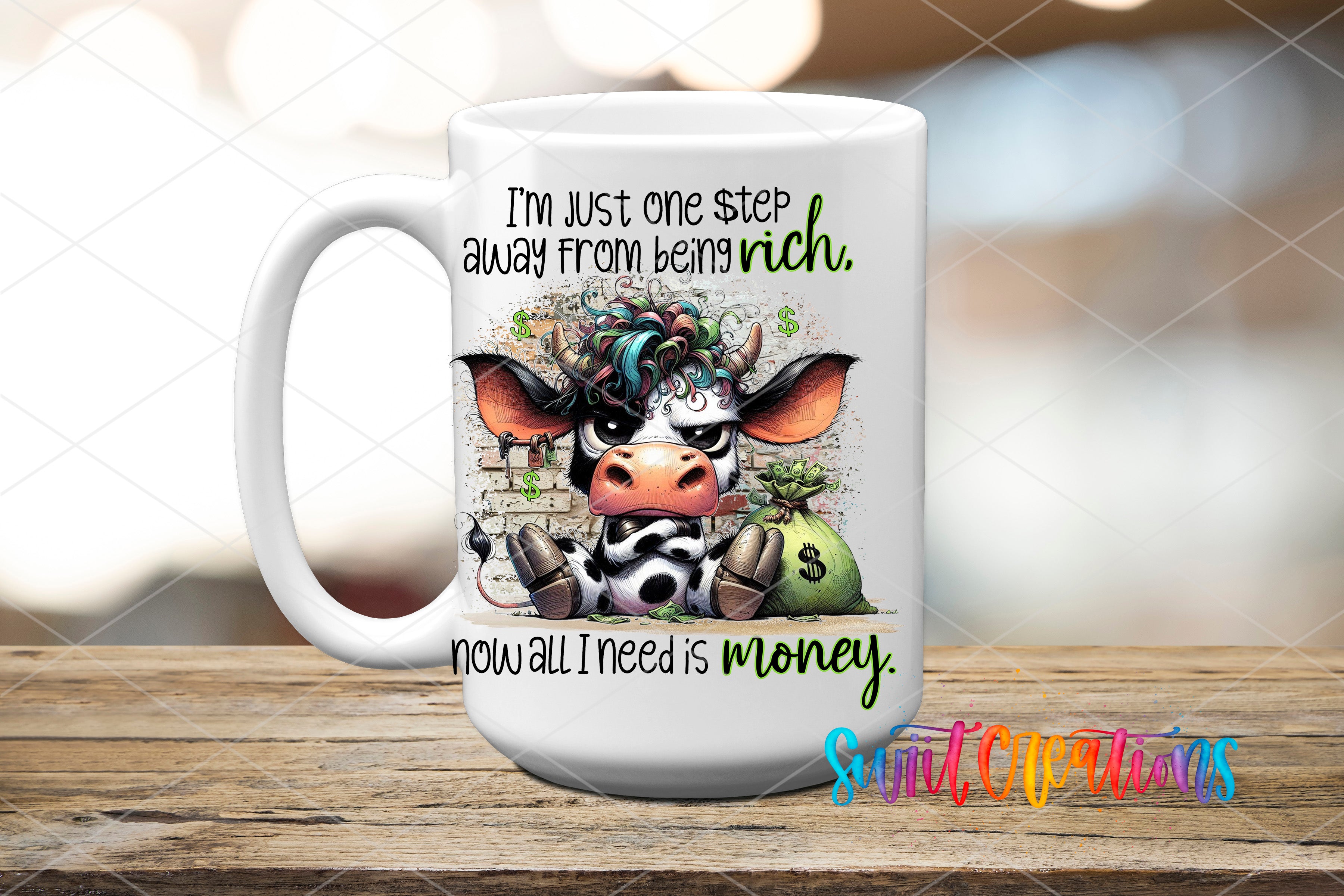 A white ceramic mug with a cow design and text on it, placed on a wooden surface.