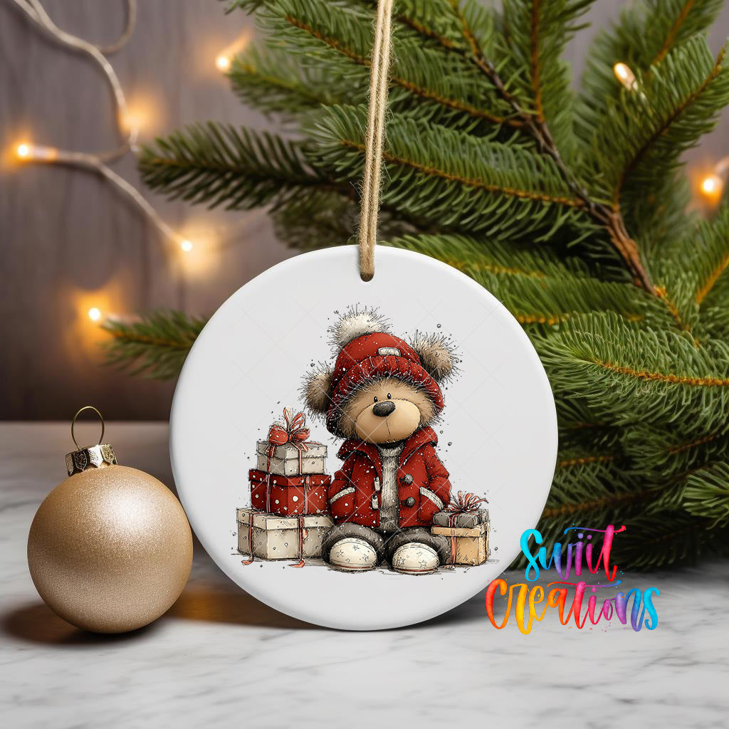 A white ceramic ornament featuring a teddy bear wearing a red coat and holding presents, surrounded by Christmas decorations and a Christmas tree.