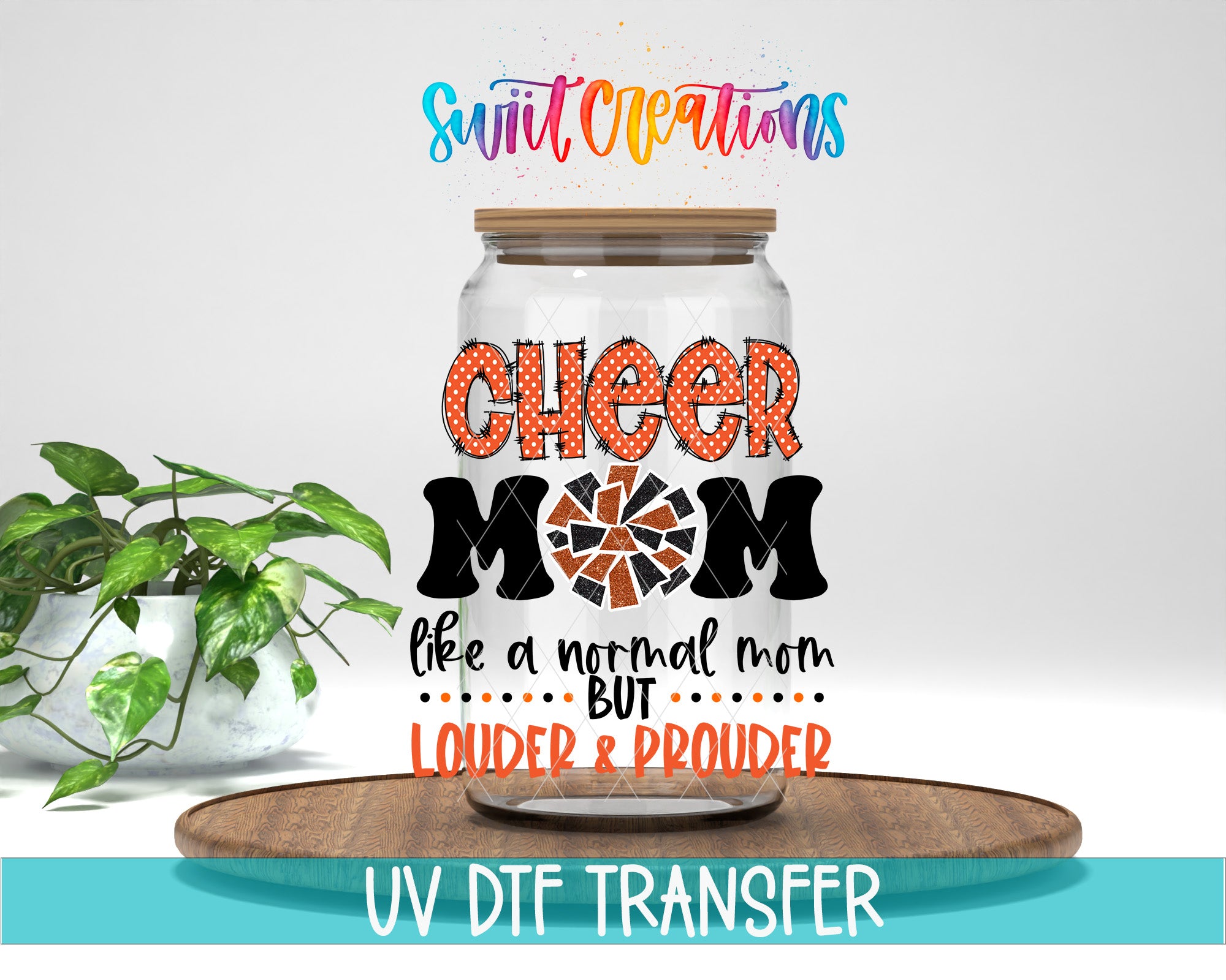 a glass jar with a lid, decorated with text that says "CHEER MOM like a normal mom but LOUDER & PROUDER". The jar is placed on a wooden tray, and there is a potted plant in the background.