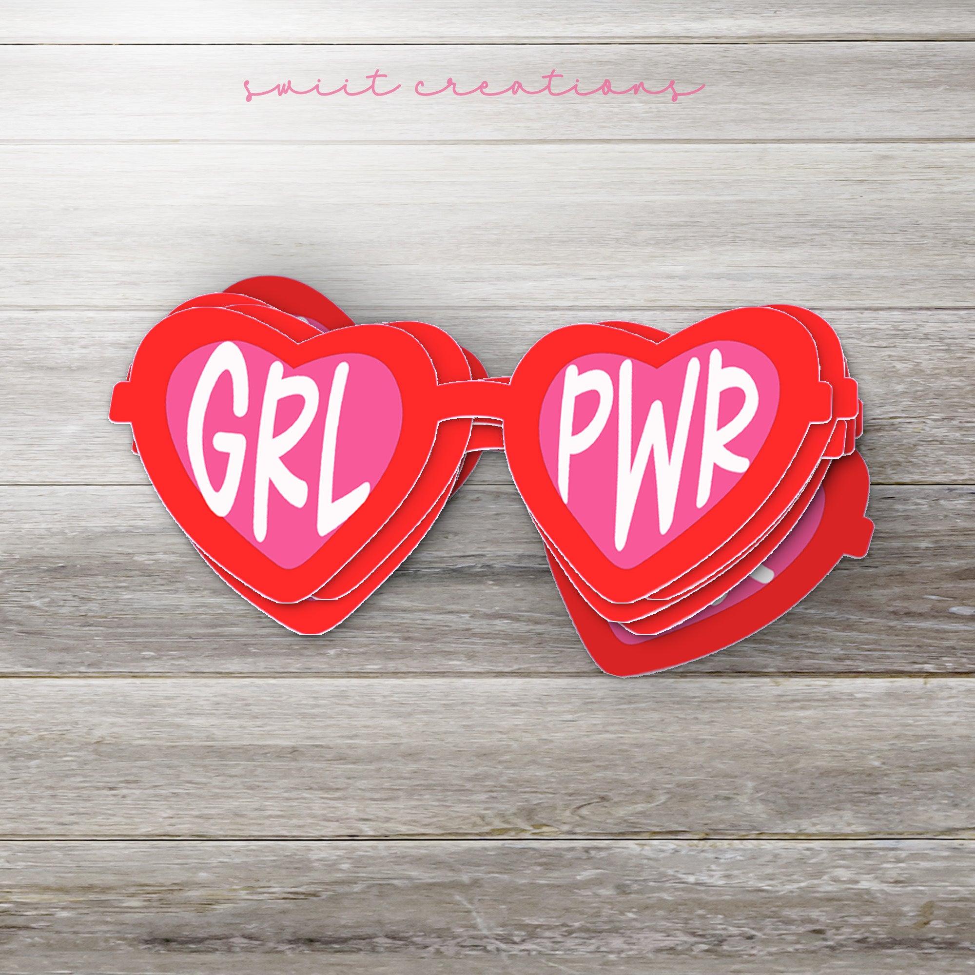 a couple of red heart shaped magnets sitting on top of a wooden table