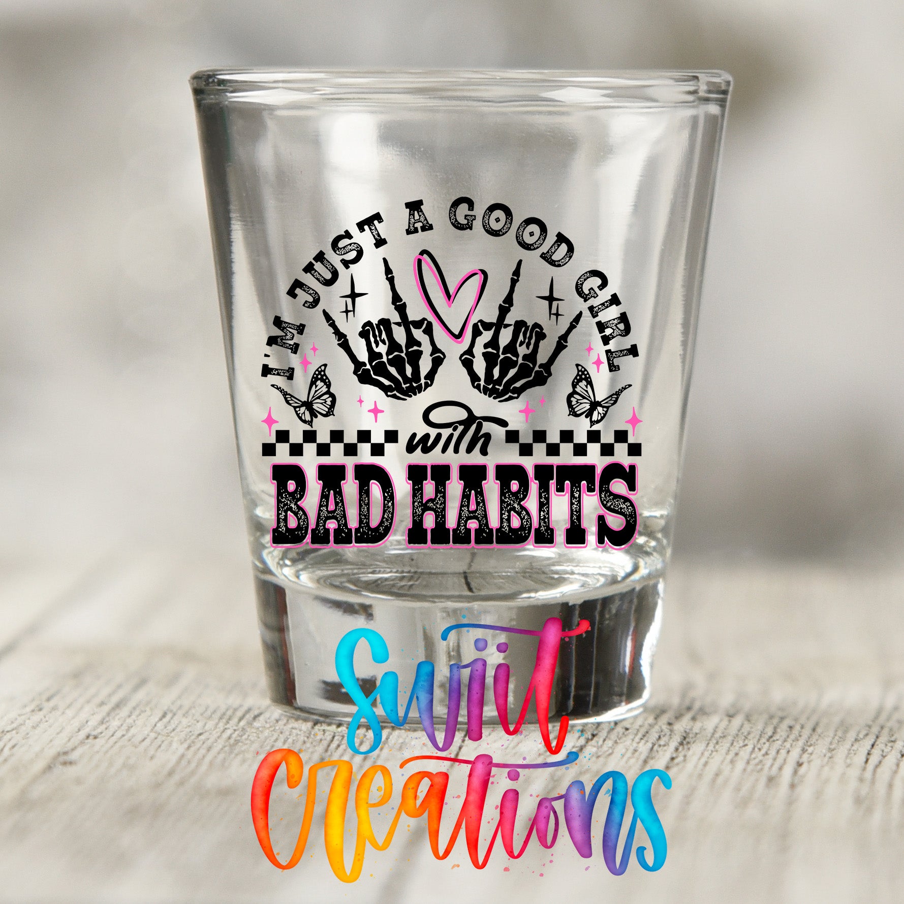 A shot glass with a printed design on it, featuring text and graphics.
