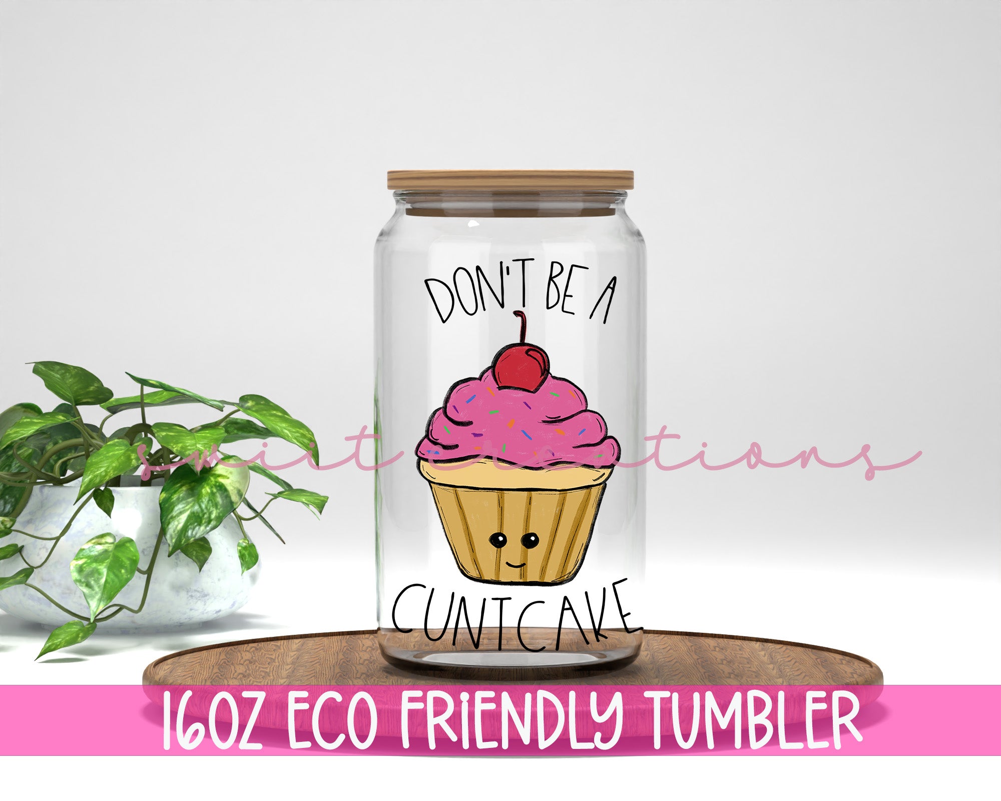 a glass jar filled with a pink cupcake on top of a wooden table