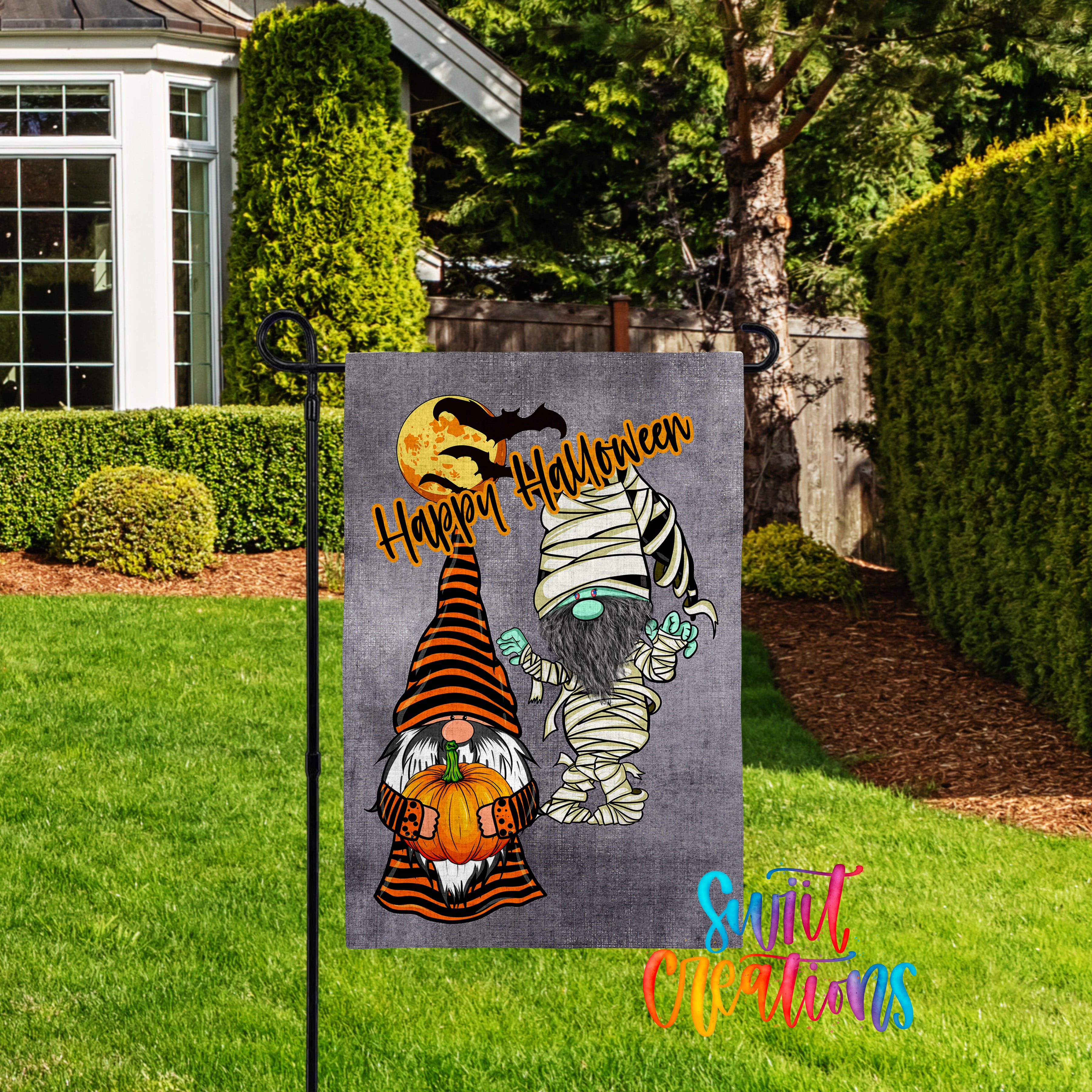 A Halloween-themed garden sign featuring two gnomes, one with a pumpkin and the other with a skeleton mask, standing in a yard with a house and trees in the background.