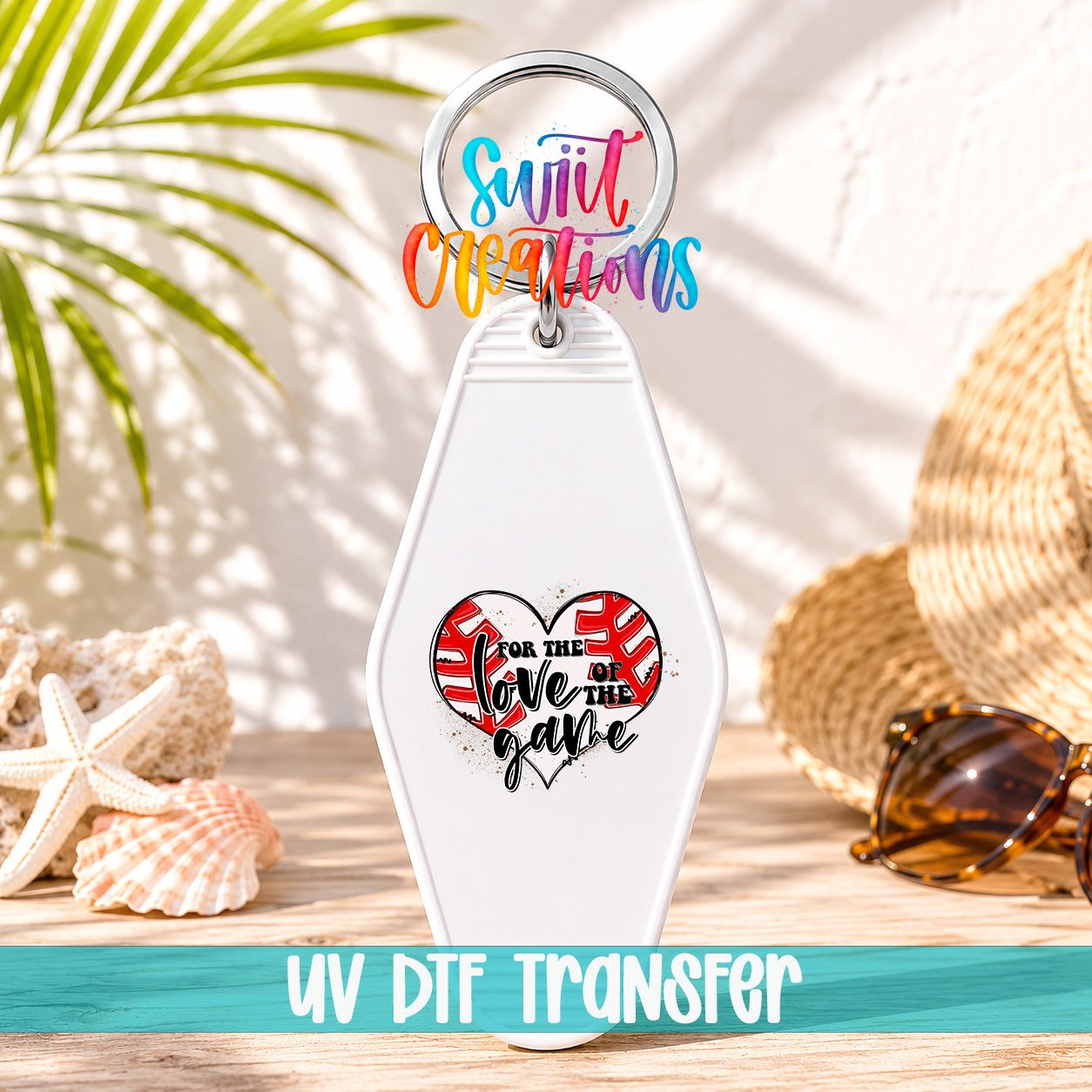A keychain with a heart-shaped design and the text "Love the game" printed on it, placed on a wooden surface with sunglasses and a straw hat in the background.