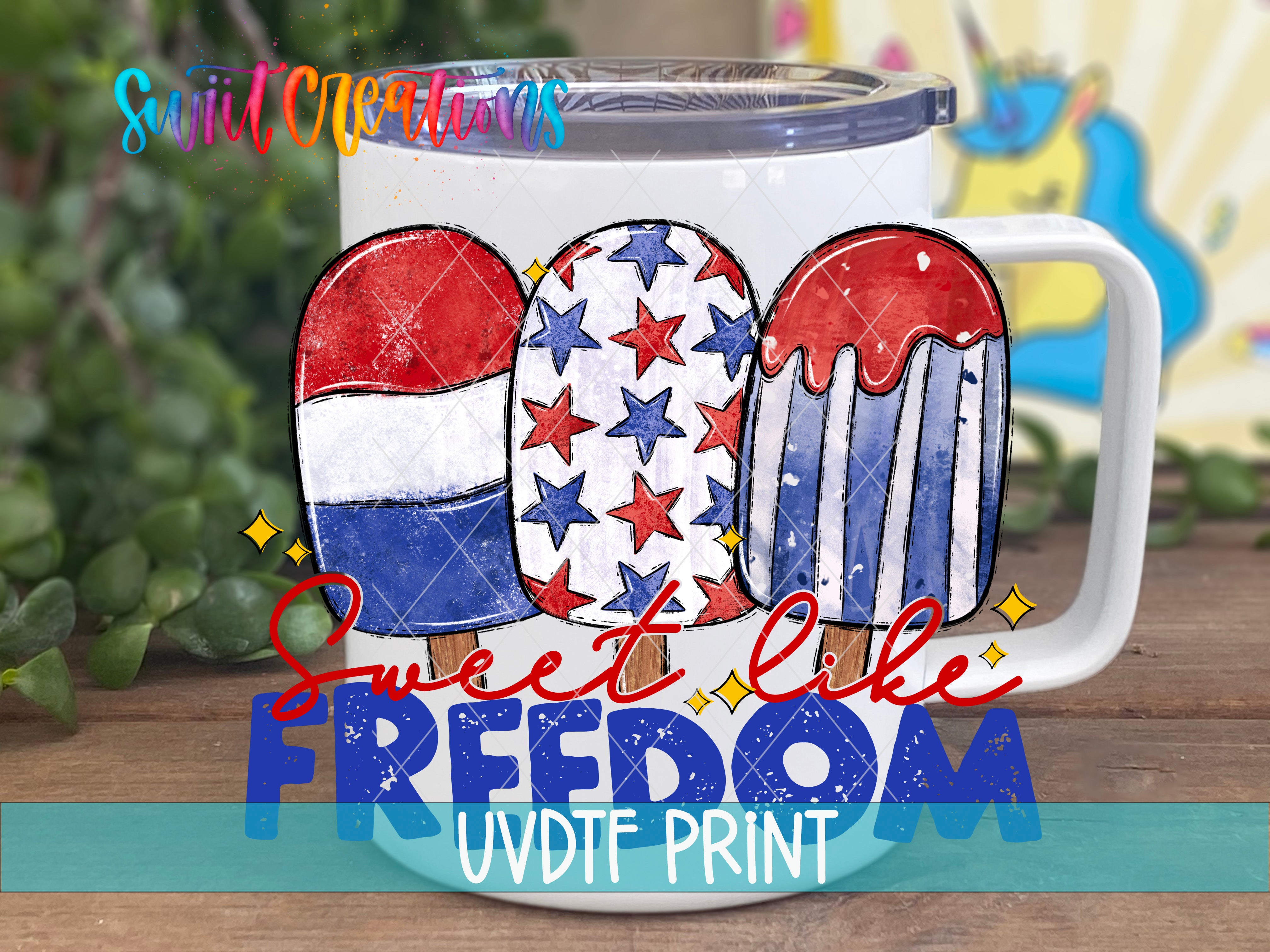 A white mug with a patriotic design featuring three popsicles in red, white, and blue colors, along with stars and stripes. The mug is placed on a wooden surface, and there is a colorful background behind it.