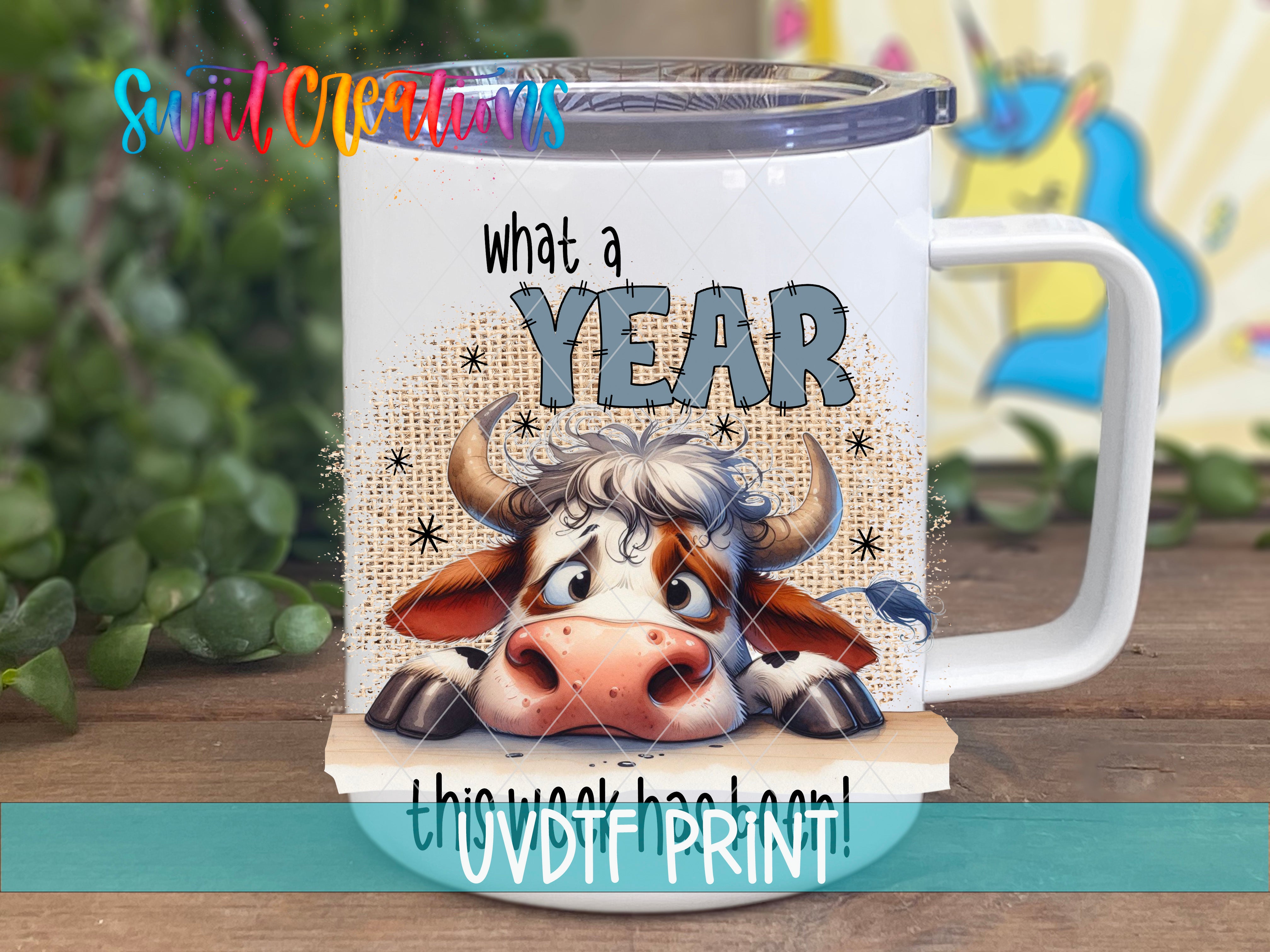 A white mug with a cartoon cow design and the text "What a YEAR" printed on it.