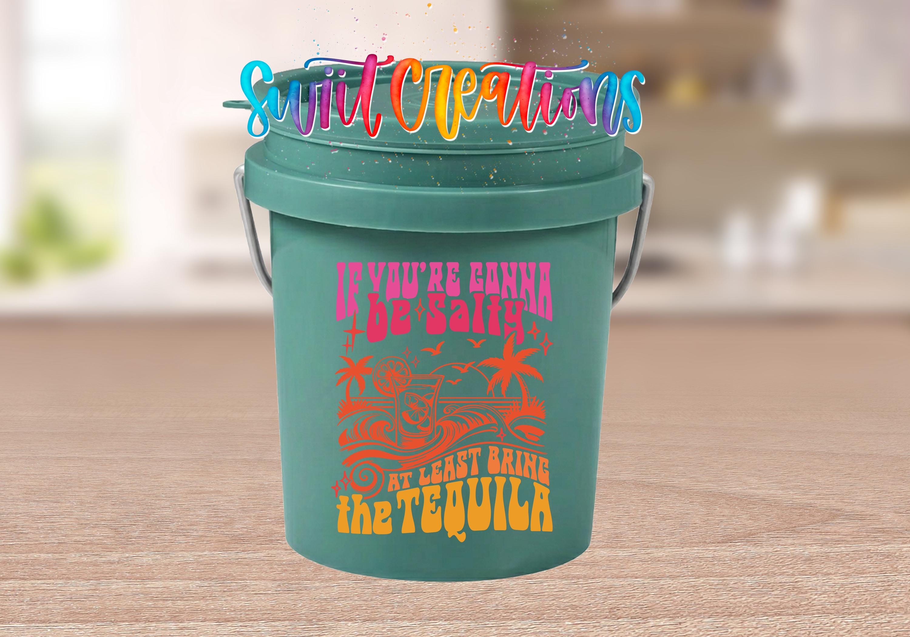 A green bucket with a colorful design and text on it, placed on a wooden surface.