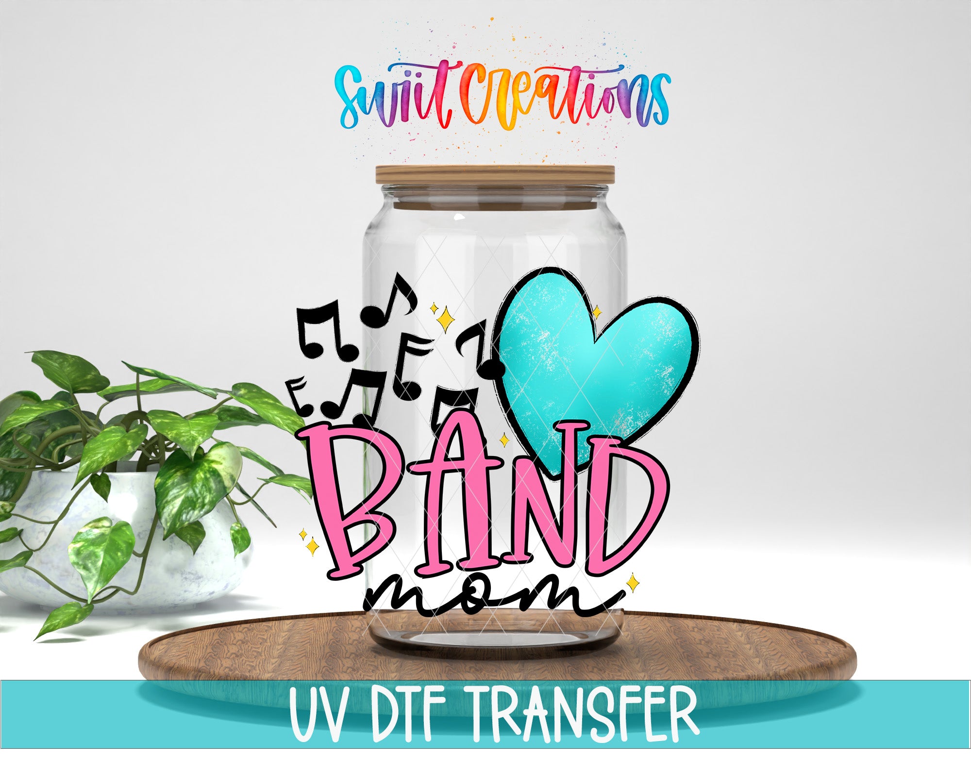 a glass jar with a heart and musical notes, along with the text "BAND mom" and "Swift Creations" written on it. The jar is placed on a wooden surface, and there is a potted plant in the background.