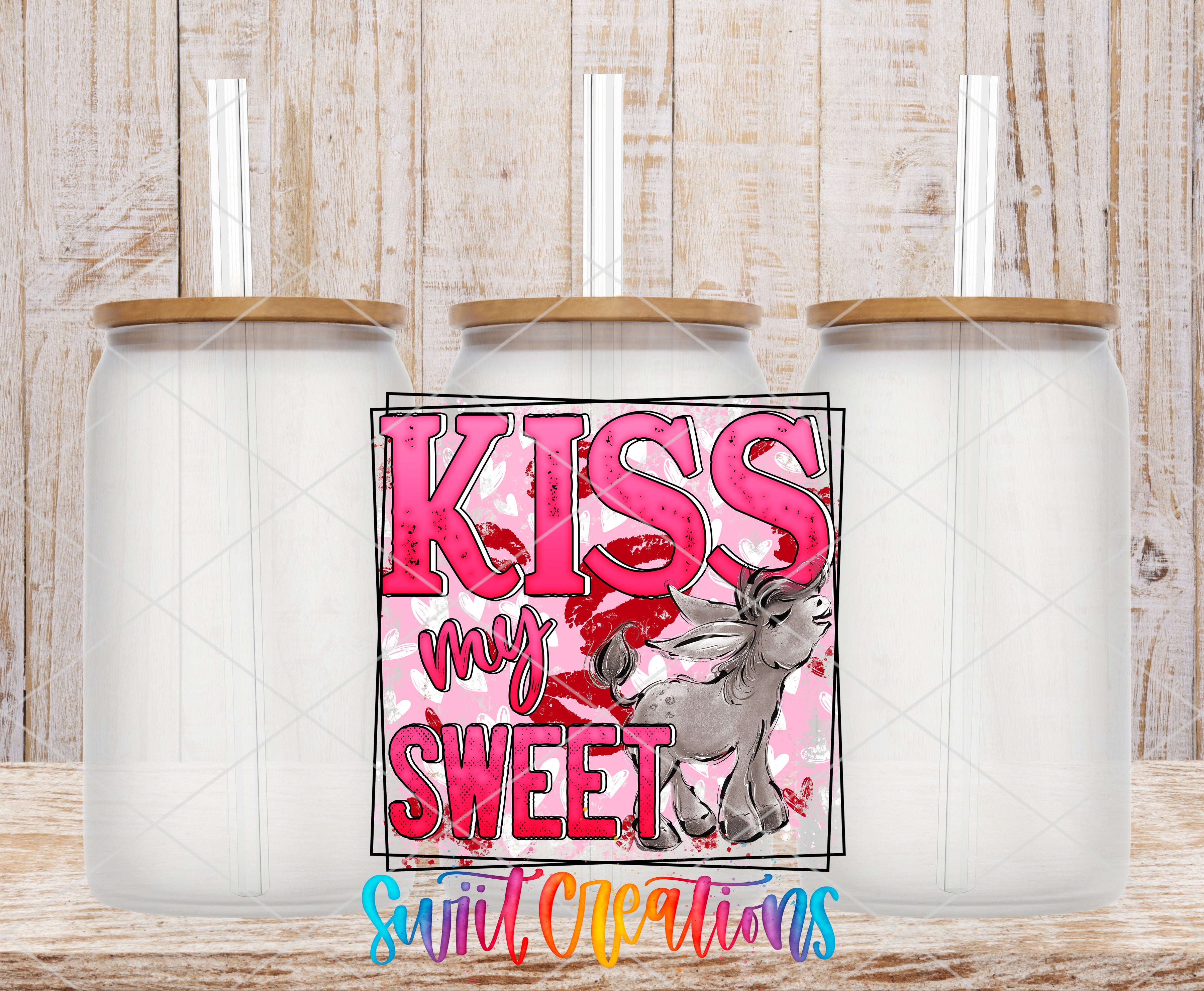 three clear glass jars with wooden lids, arranged in a row against a wooden background. The jars have a pink and white color scheme, and there is a graphic design in the center that includes the text "KISS my sweet" and an illustration of a unicorn.