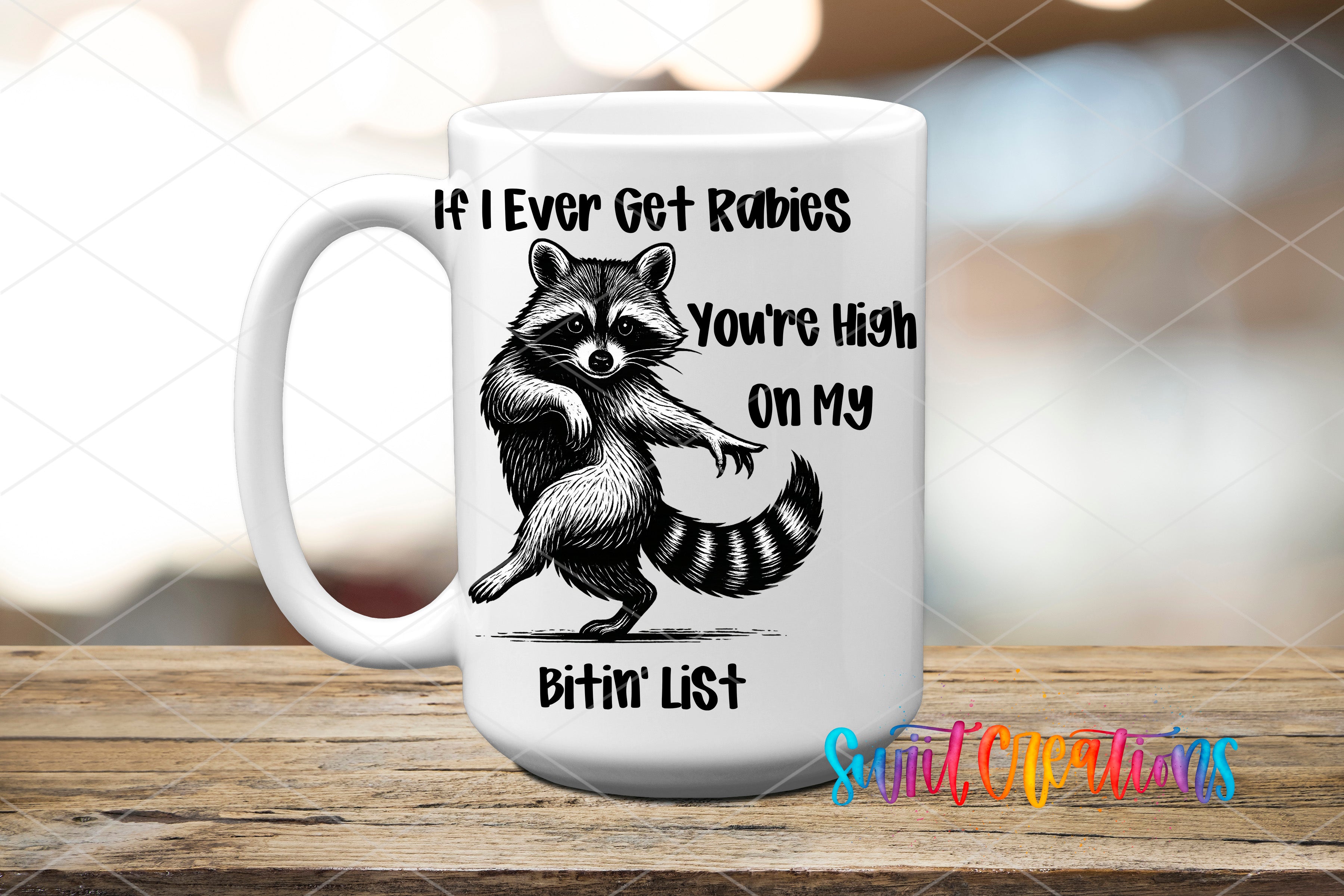 A white ceramic mug with a raccoon illustration and text that reads "If I ever get Rabies, you're high on my Bitim List".