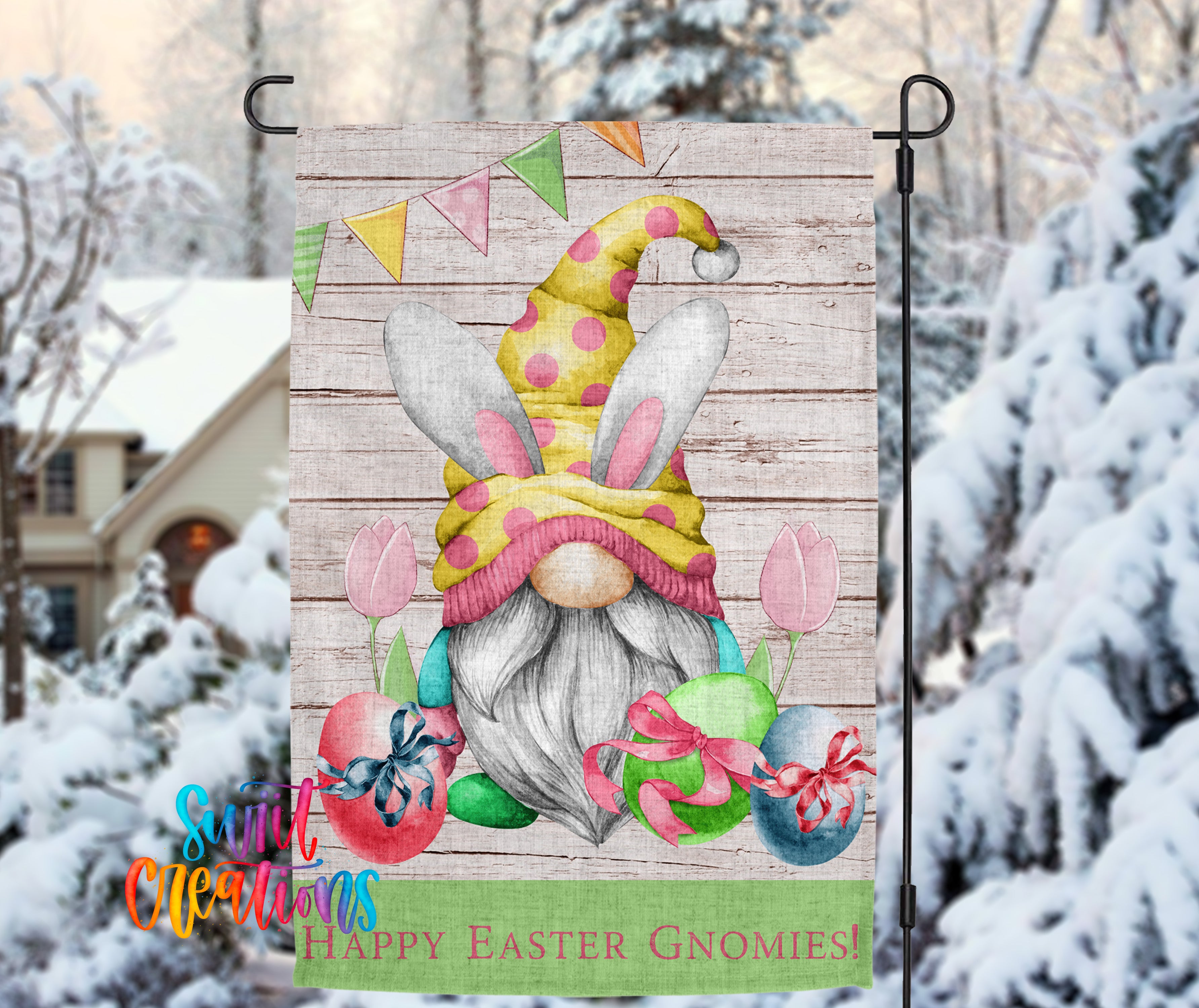 A colorful Easter-themed garden gnome flag is displayed in a snowy outdoor setting, featuring a bunny hat, flowers, and Easter eggs.