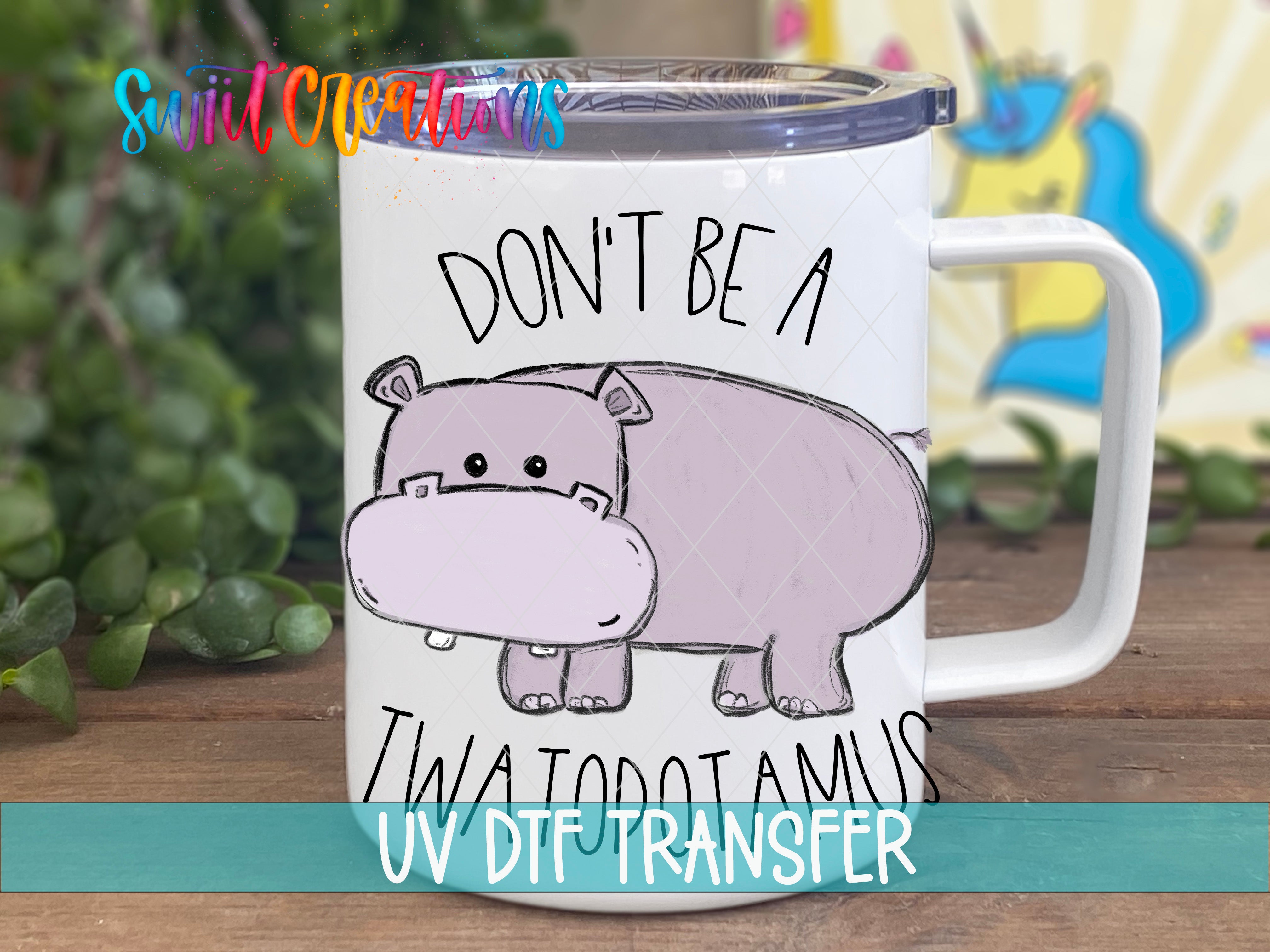 A white mug with a cartoon image of a hippopotamus and the text "DON'T BE A TWATOTAMUS" printed on it.