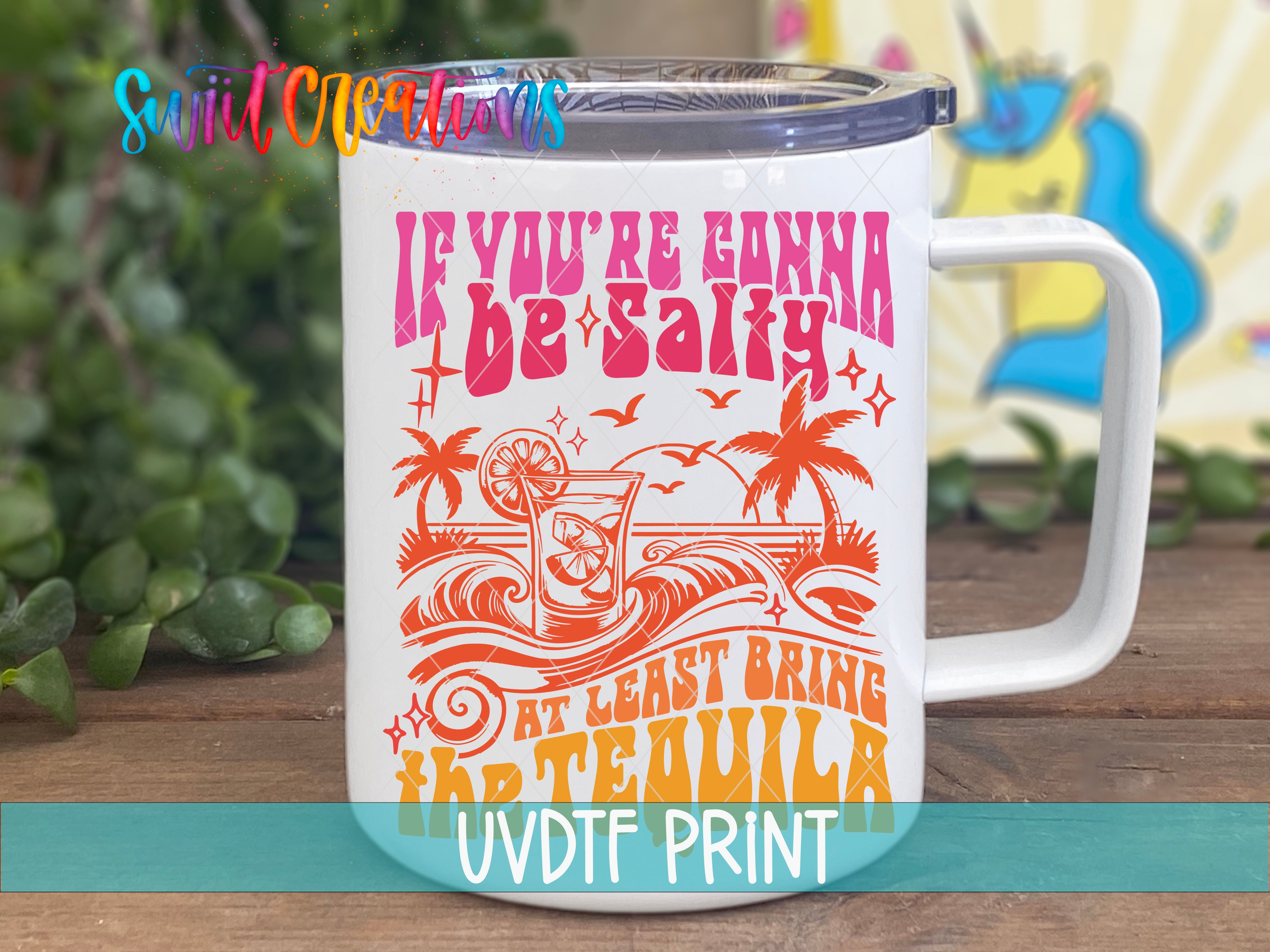 A white mug with a colorful design and text printed on it, placed on a wooden surface.