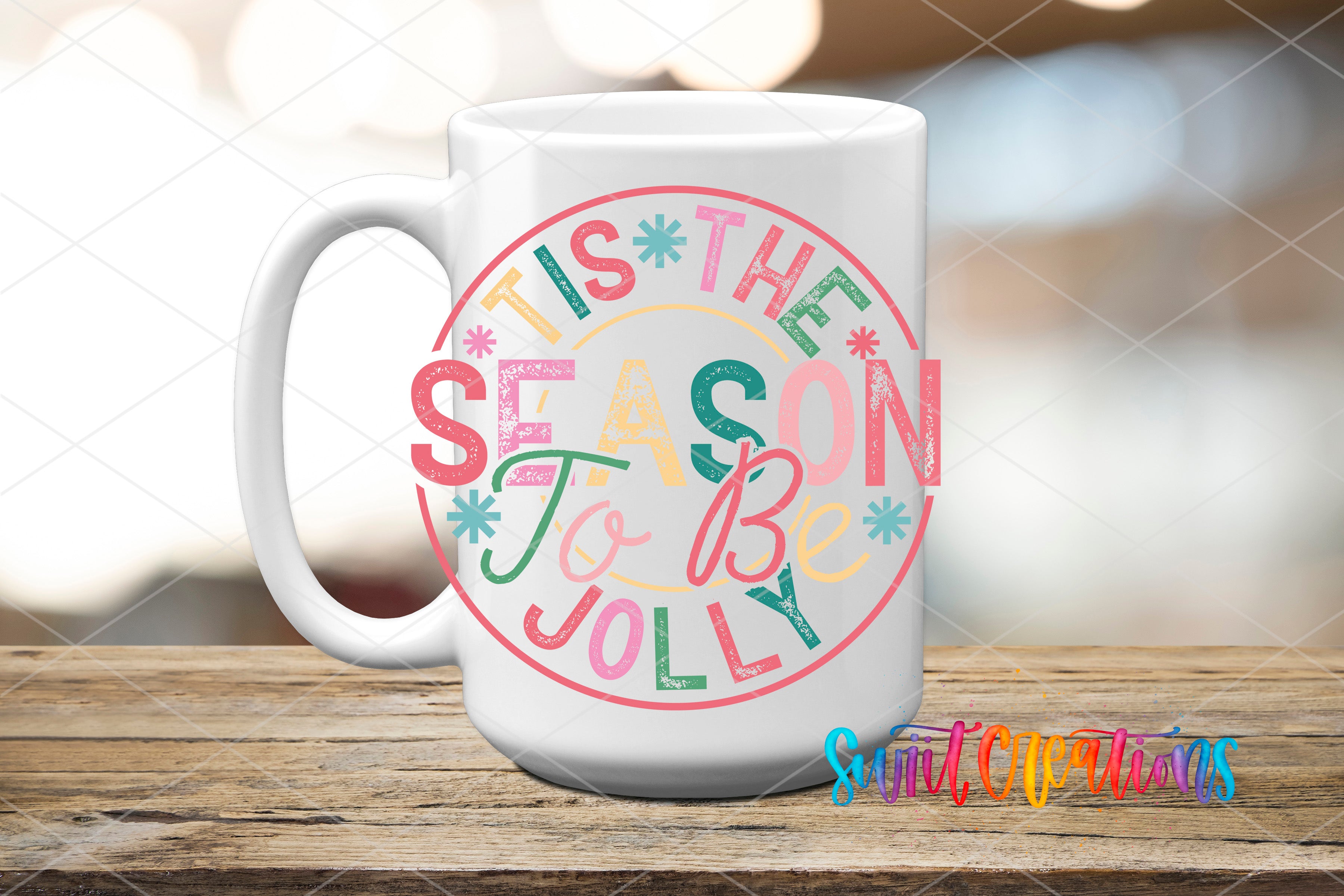 A white mug with a colorful design featuring the text "TIS THE SEASON TO BE JOYOUS" in a circular pattern.