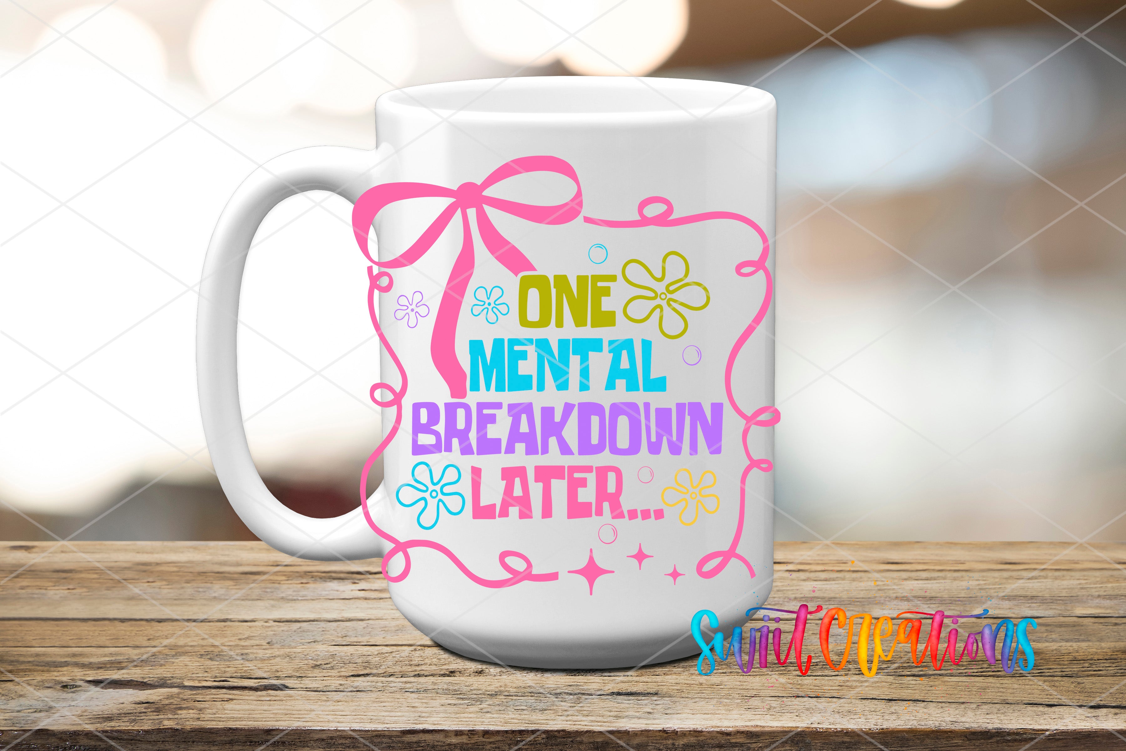 A white mug with a colorful design and text on it, placed on a wooden surface.