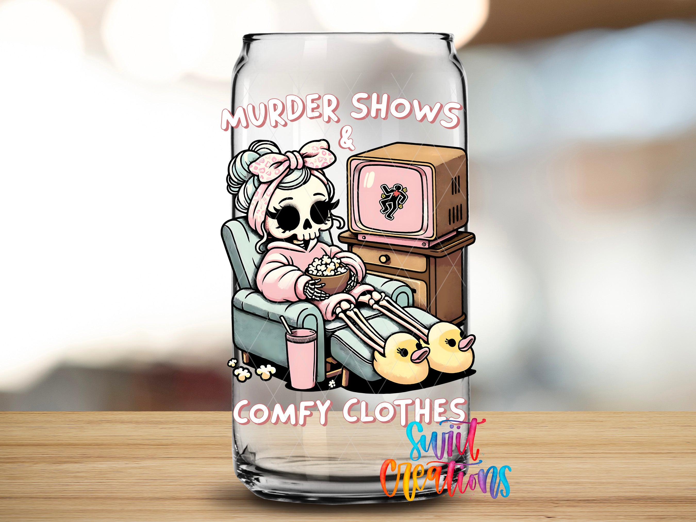A glass can with a cartoon illustration of a skeleton wearing a pink outfit and holding a cup of popcorn, sitting in a chair and watching television.
