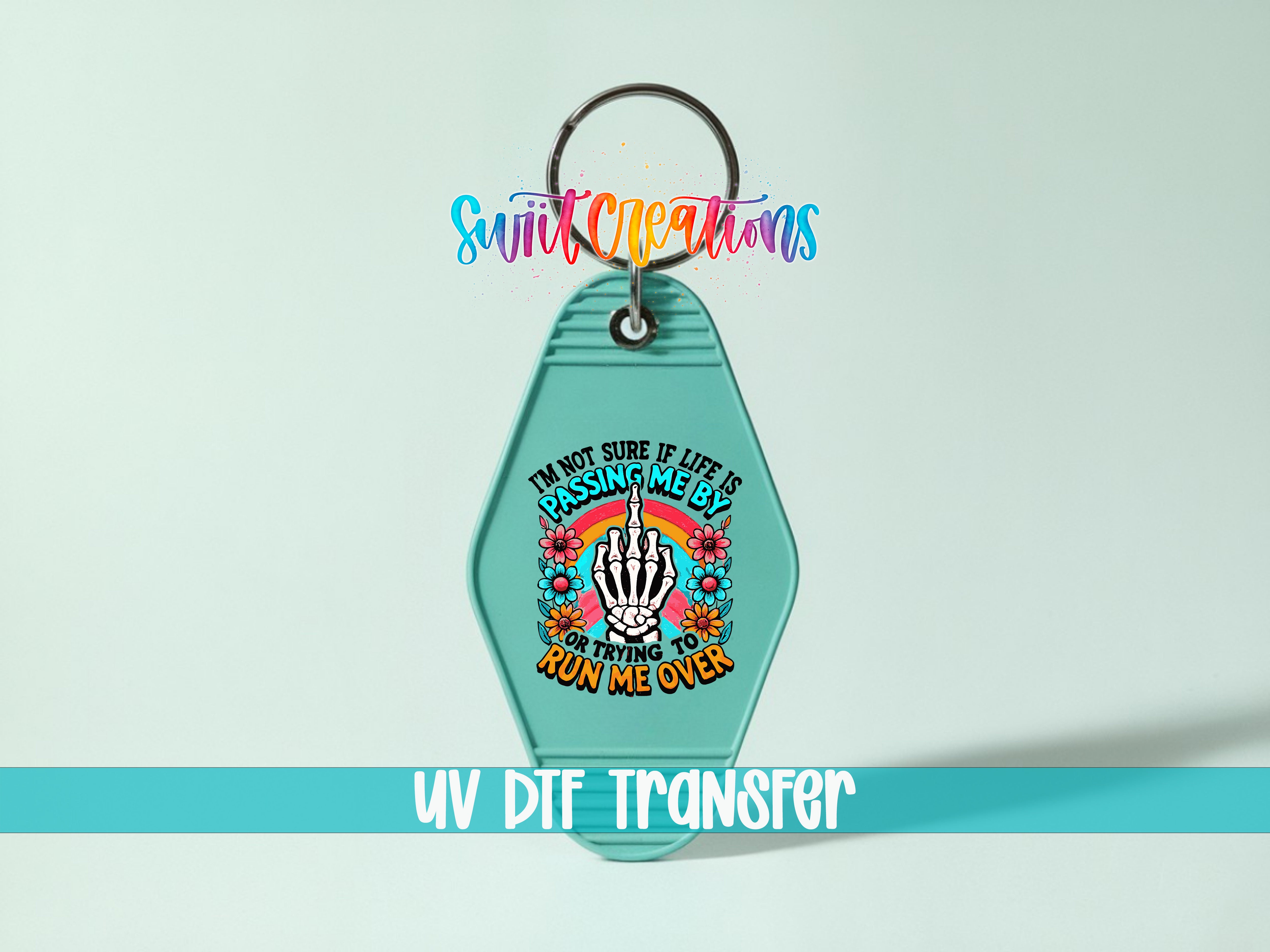 A keychain with a colorful design featuring a skeleton hand and text that reads "I'm not sure if life is passing me by, but I'm trying to run me over".