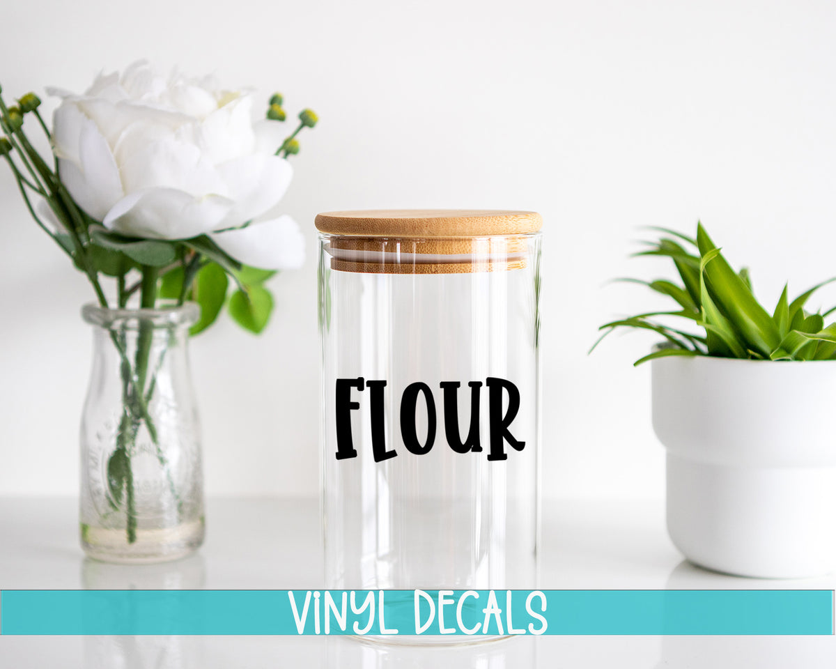a glass jar with a wooden lid sitting next to a vase with flowers in it