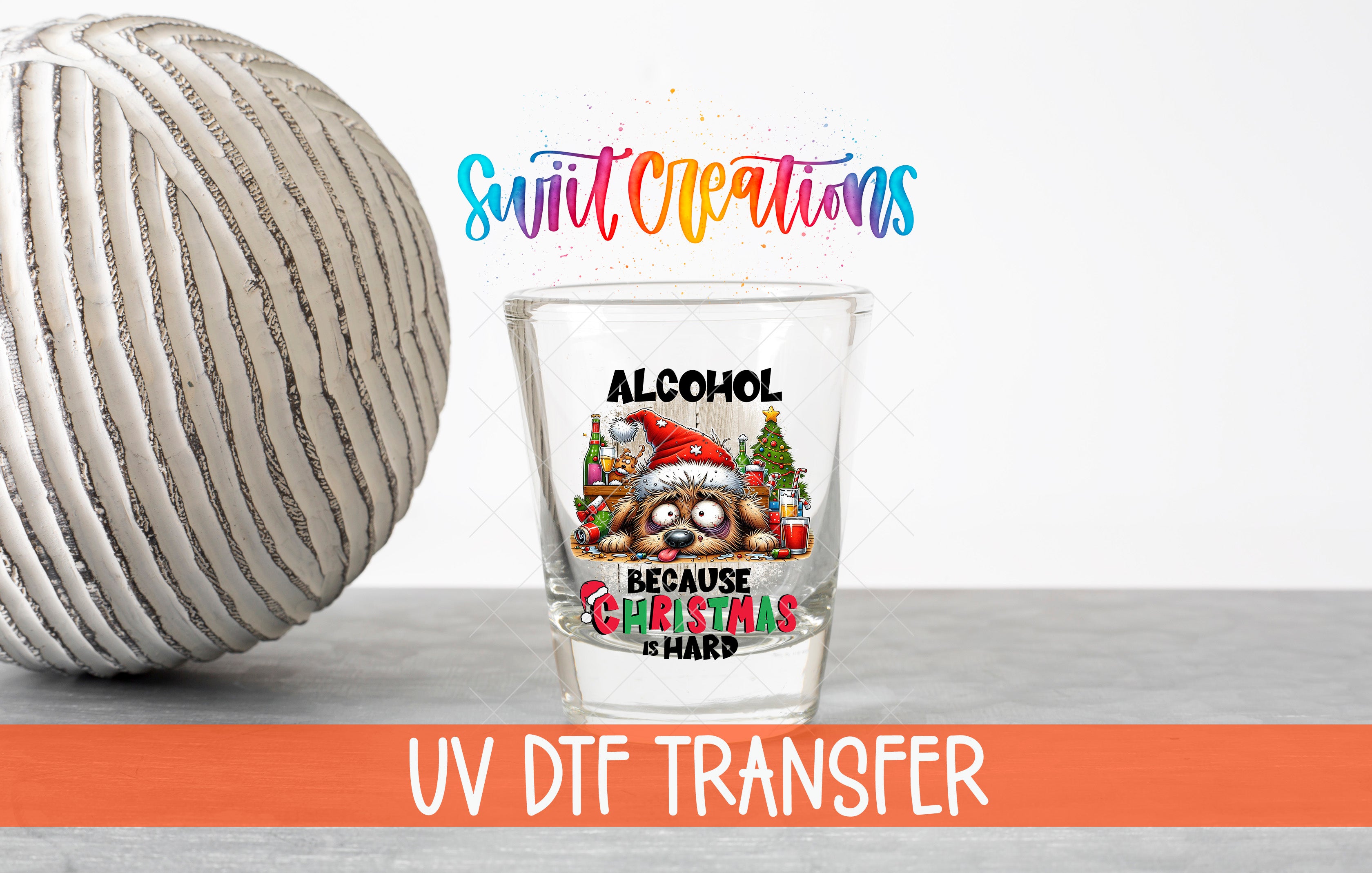 a glass with a Christmas-themed design, including a Santa hat and a Christmas tree, along with the text "ALCOHOL BECAUSE CHRISTMAS IS HARD" and "UV DFT TRANSFER".